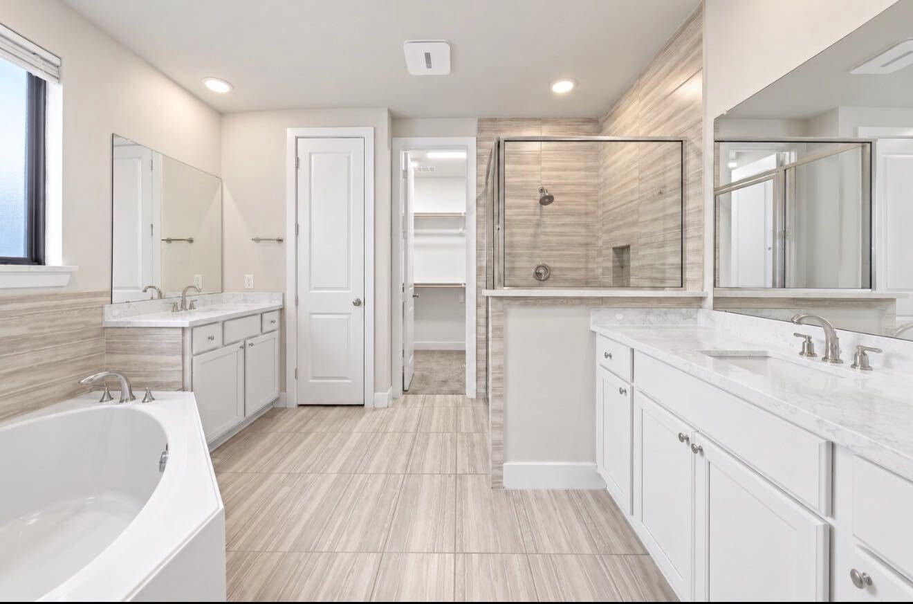 9231 Dearborn Knoll Drive, Cypress, TX 77433 The primary bath offers double vanities, a soaking tub, a separate glass-enclosed shower, and direct access to the walk-in closet, which makes daily routines easy.