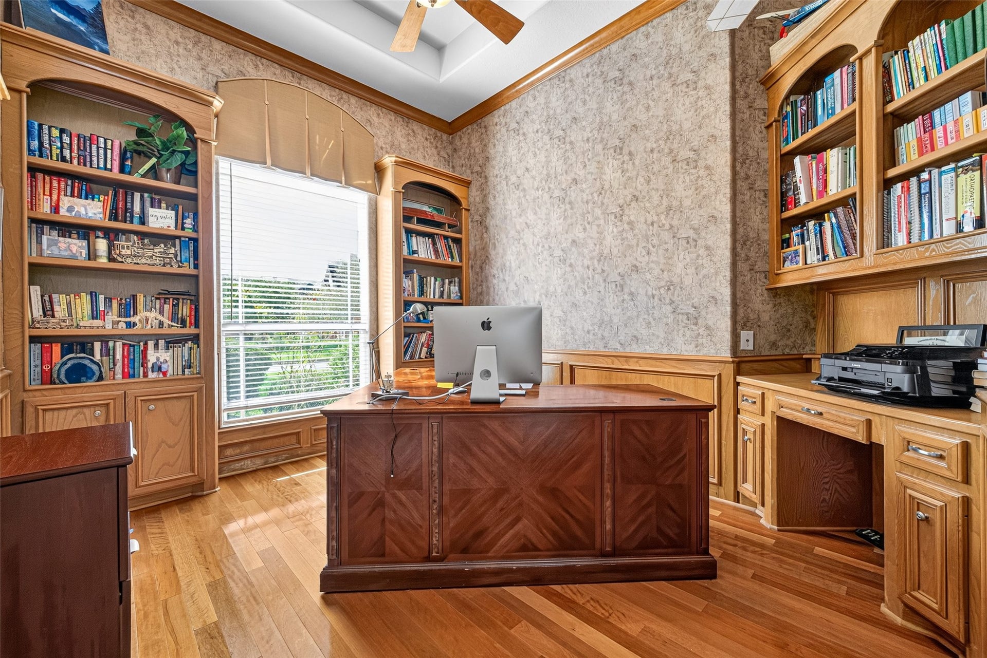 Executive study features wood floors, solid wood shelving, high ceilings, a ceiling fan and plenty of shelving