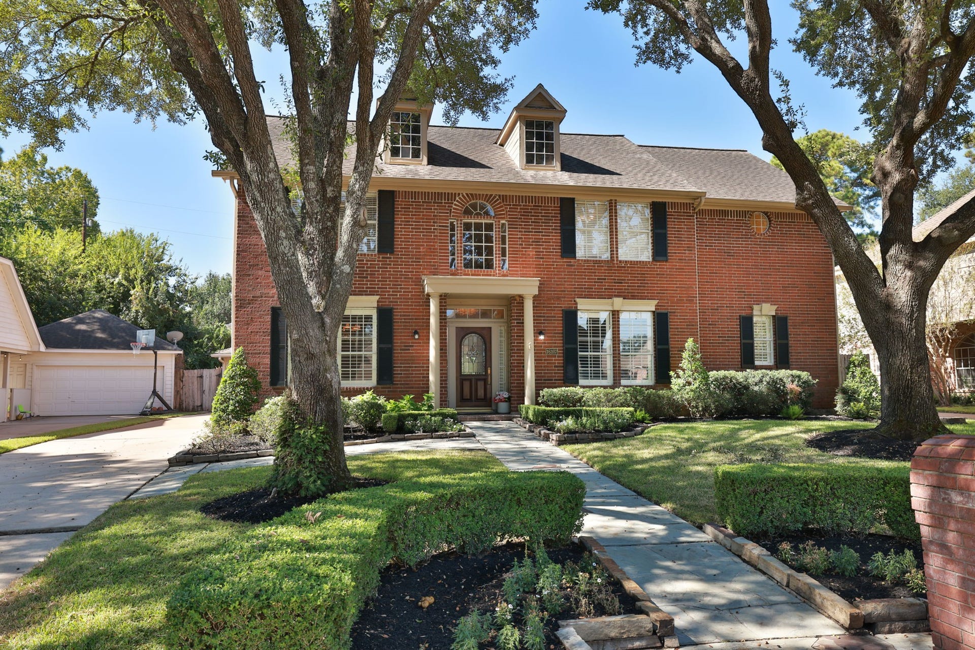 16107 Abberton Hill Drive, Spring, TX 77379 Perfectly balanced architecture with columned entry, black shutters, and freshly edged landscaping.