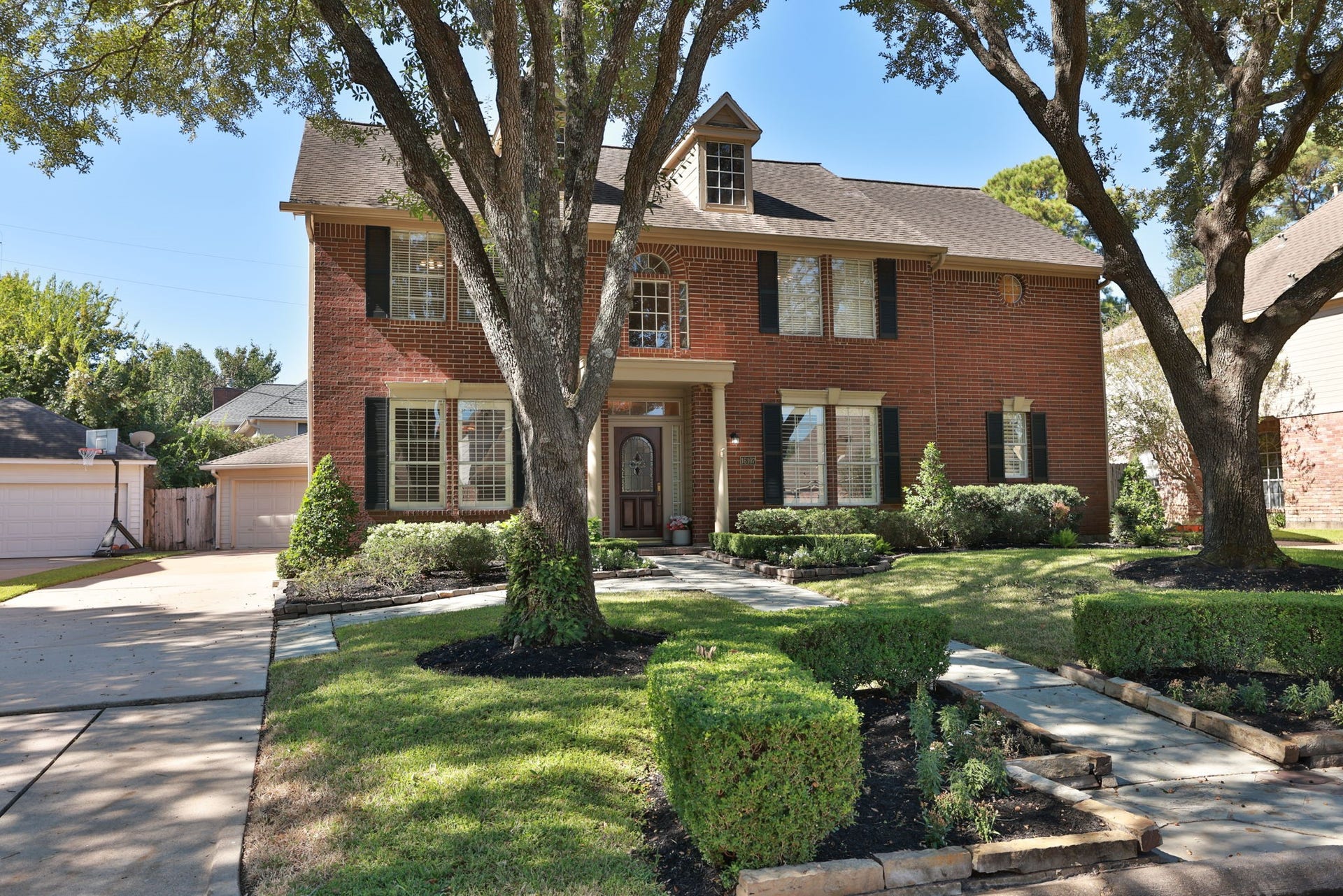 16107 Abberton Hill Drive, Spring, TX 77379 Impressive exterior with extended driveway leading to a detached two-car garage and gated side yard access.