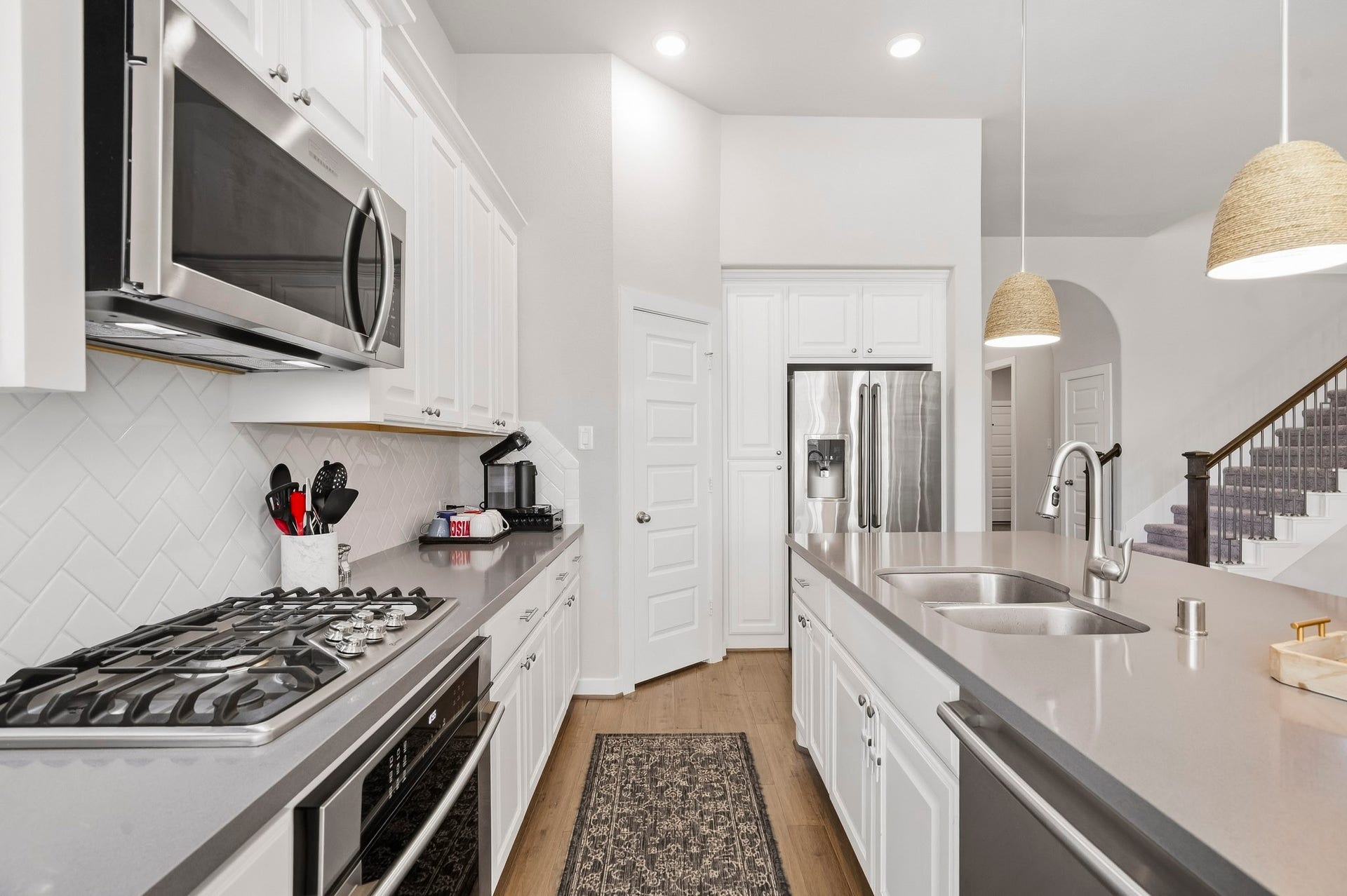 Youll love the details of this kitchen! With quartz countertops, custom pendant lighting, elegant tiled backsplash, and gas range, its perfect for everyday life or entertaining family and friends.