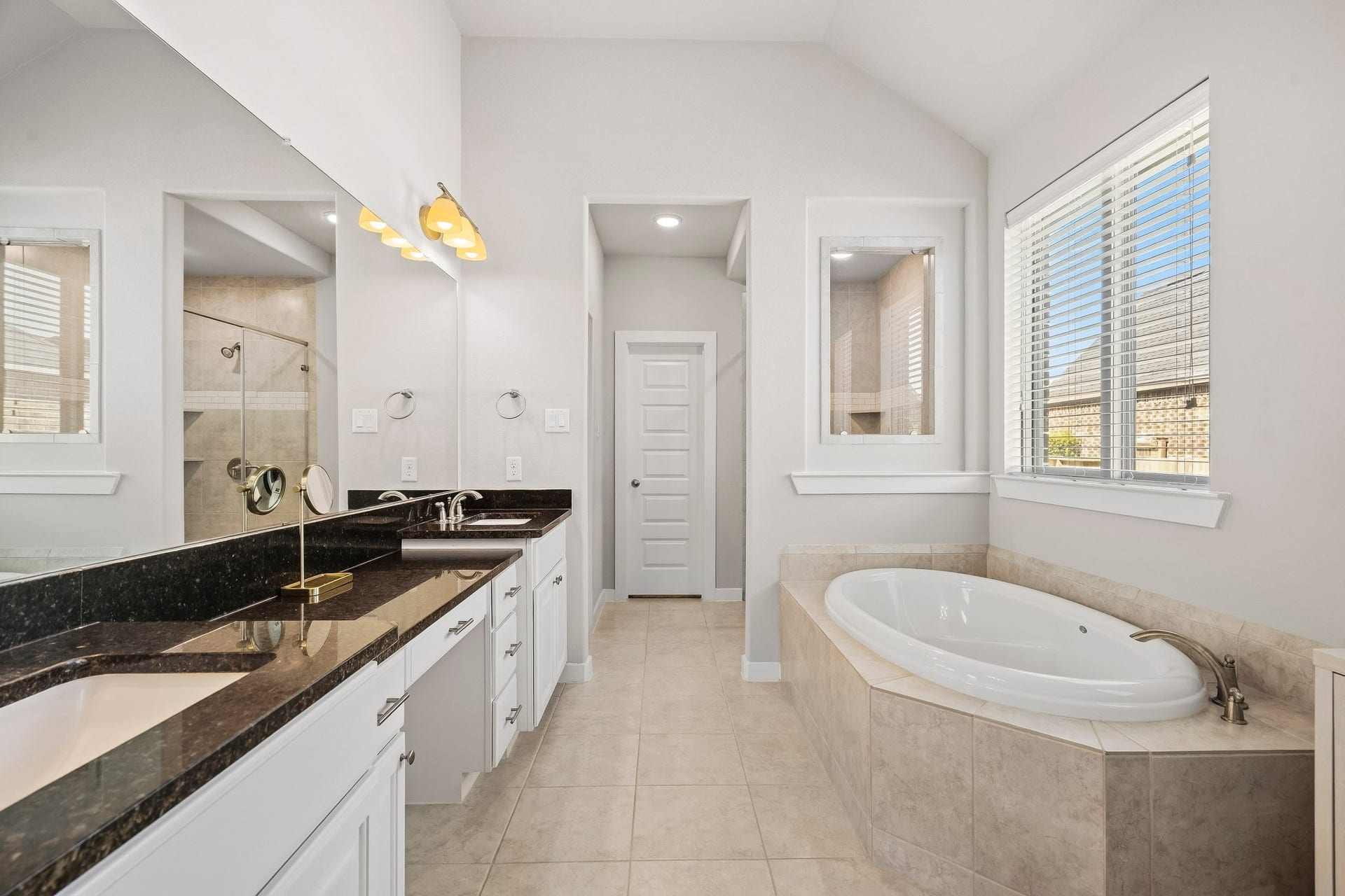 Step into comfort and style in this beautiful primary bathroom! Featuring a spacious walk-in shower with mud-set tile floors & glass surround, a serene garden tub, and spacious vanity. Natural light completes the warm and inviting feel!