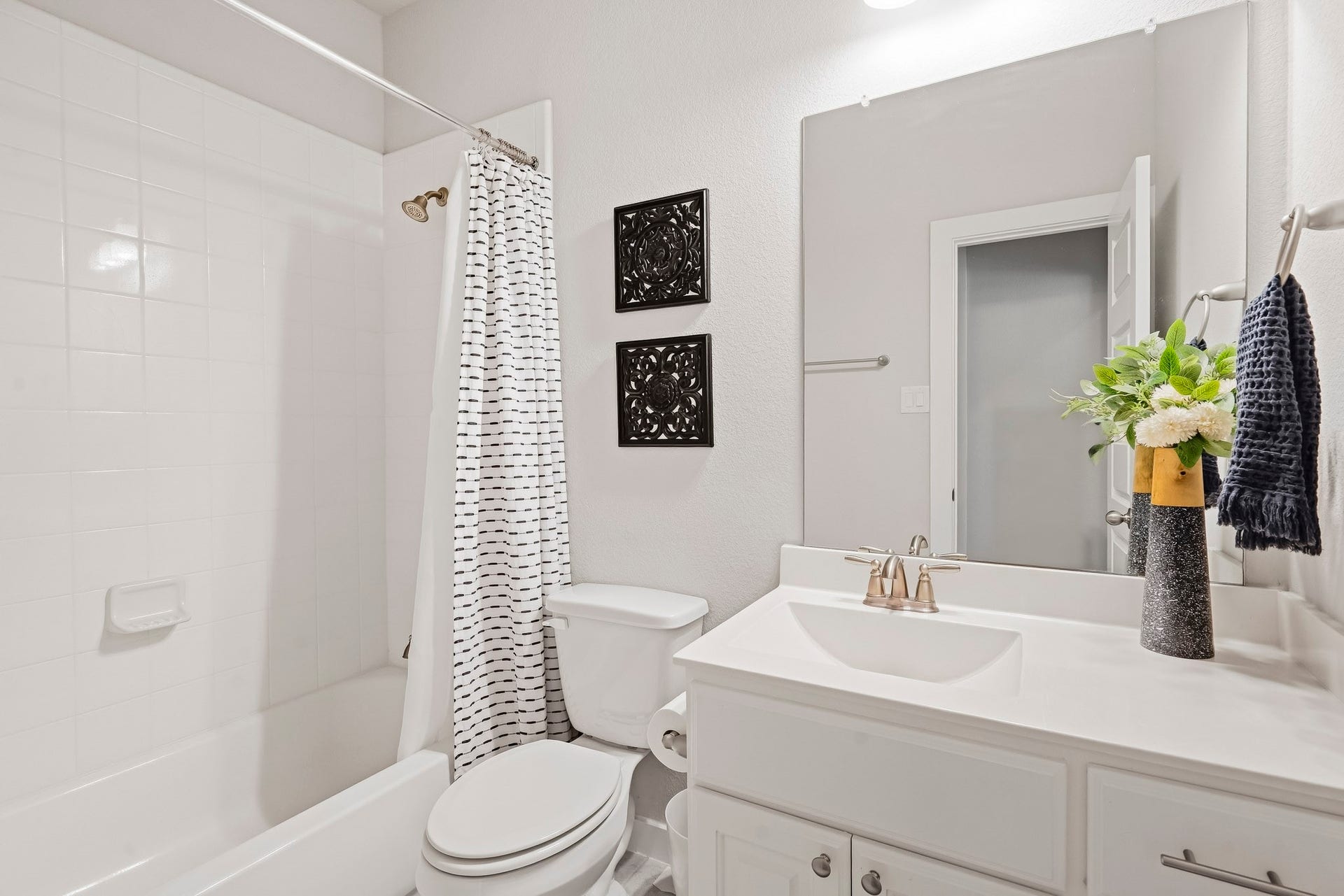 This full bathroom is located off the hall of the secondary bedrooms making it easy to share and get ready. It features a large vanity, white cabinets, quartz countertops, and a large combination tub and shower.