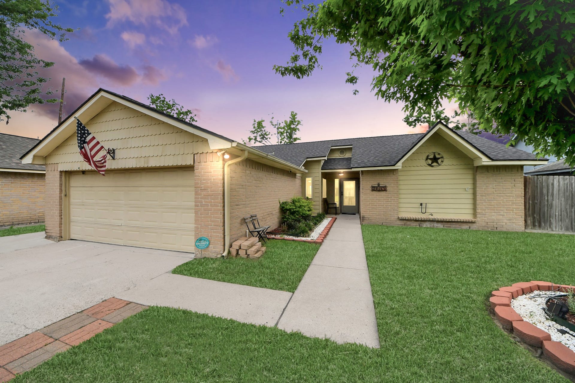 Charming single-story home with a welcoming front entrance, neatly landscaped yard, and a spacious two-car garage. The exterior features a blend of brick and siding, and there are mature trees providing shade. A pathway leads to the inviting front door.