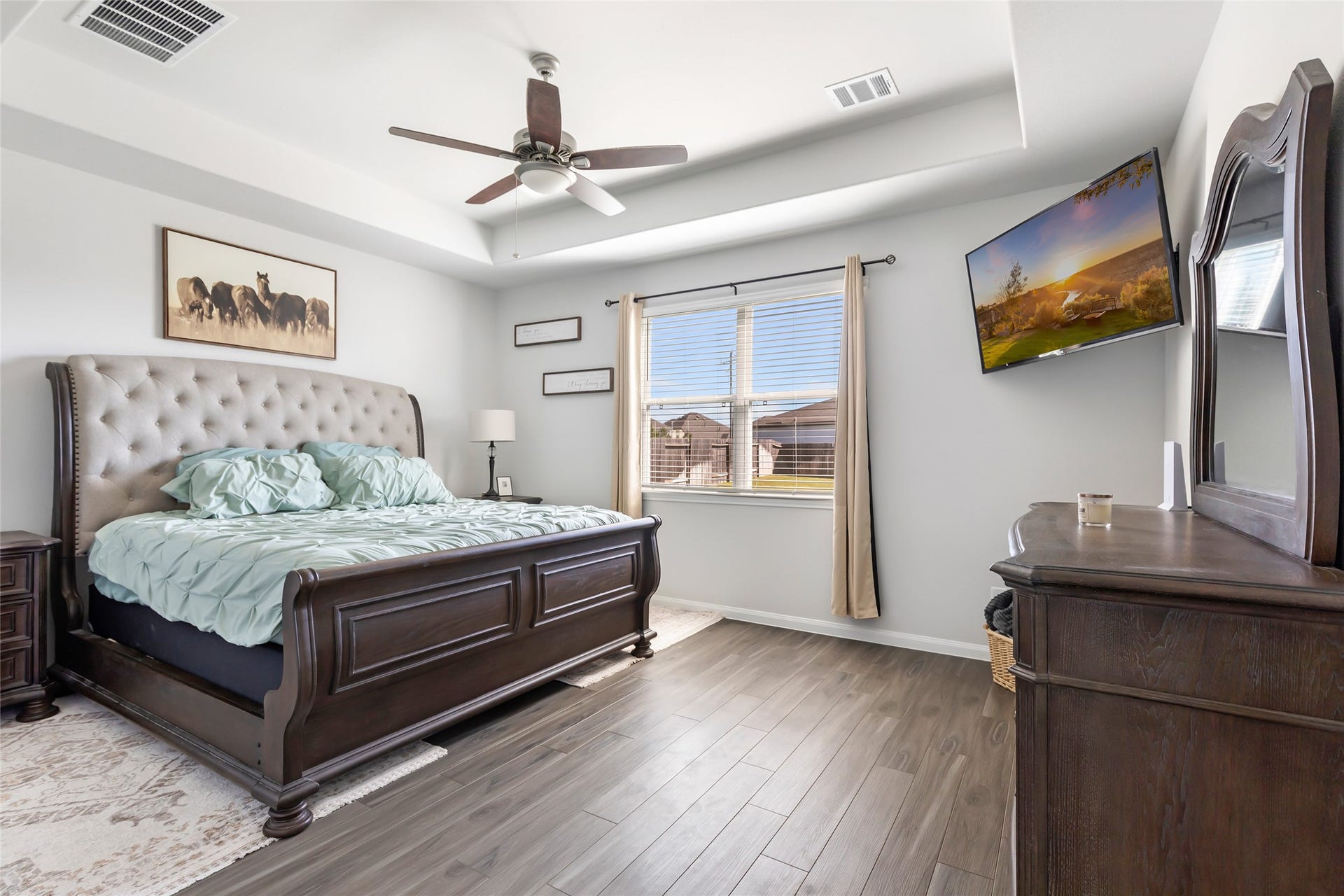 Experience elegance in the primary bedroom with sleek vinyl plank flooring and sophisticated tray ceilings.