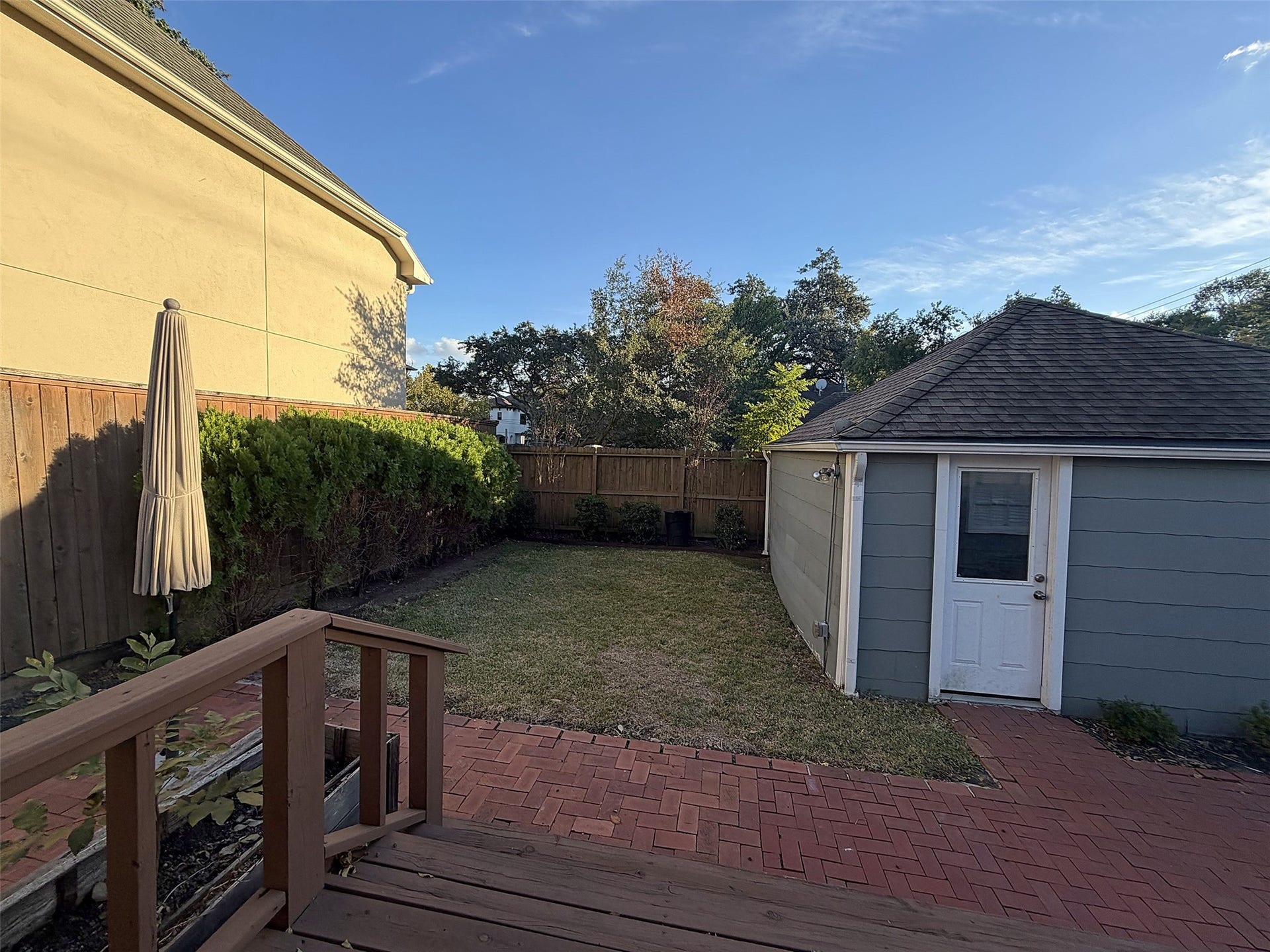 Backyard Overview: Fenced backyard with green lawn, mature trees, and outdoor entertaining space.