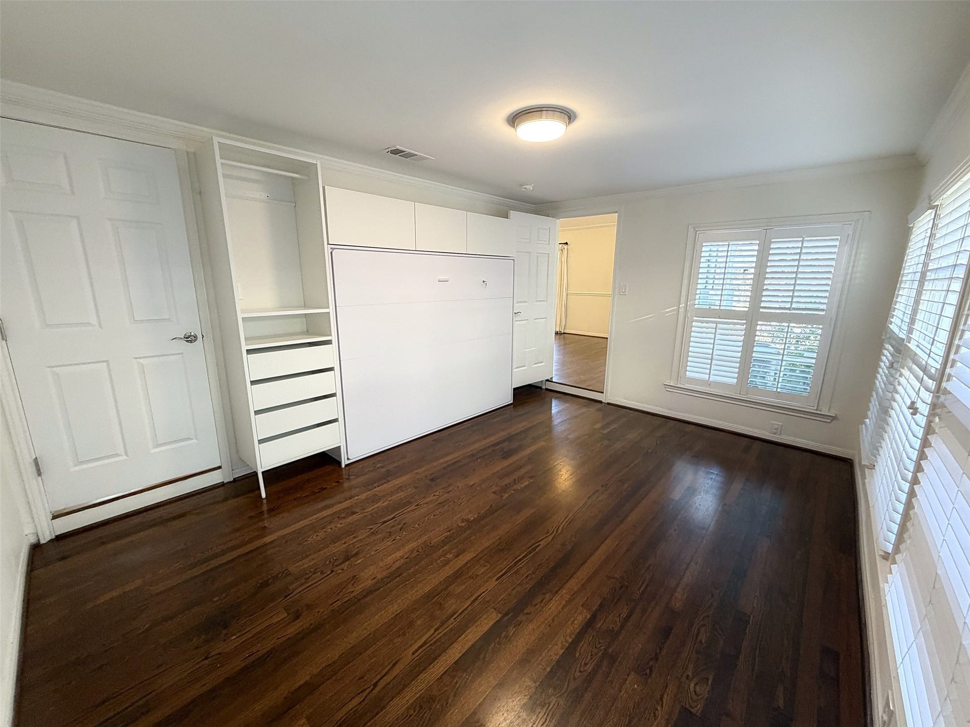 Bedroom/Study: Flexible room featuring a desk, comfortable seating, and natural light, ideal for a home office.  There is a built-in Murphy bed with integrated drawers and shelving for the weekend visitor.