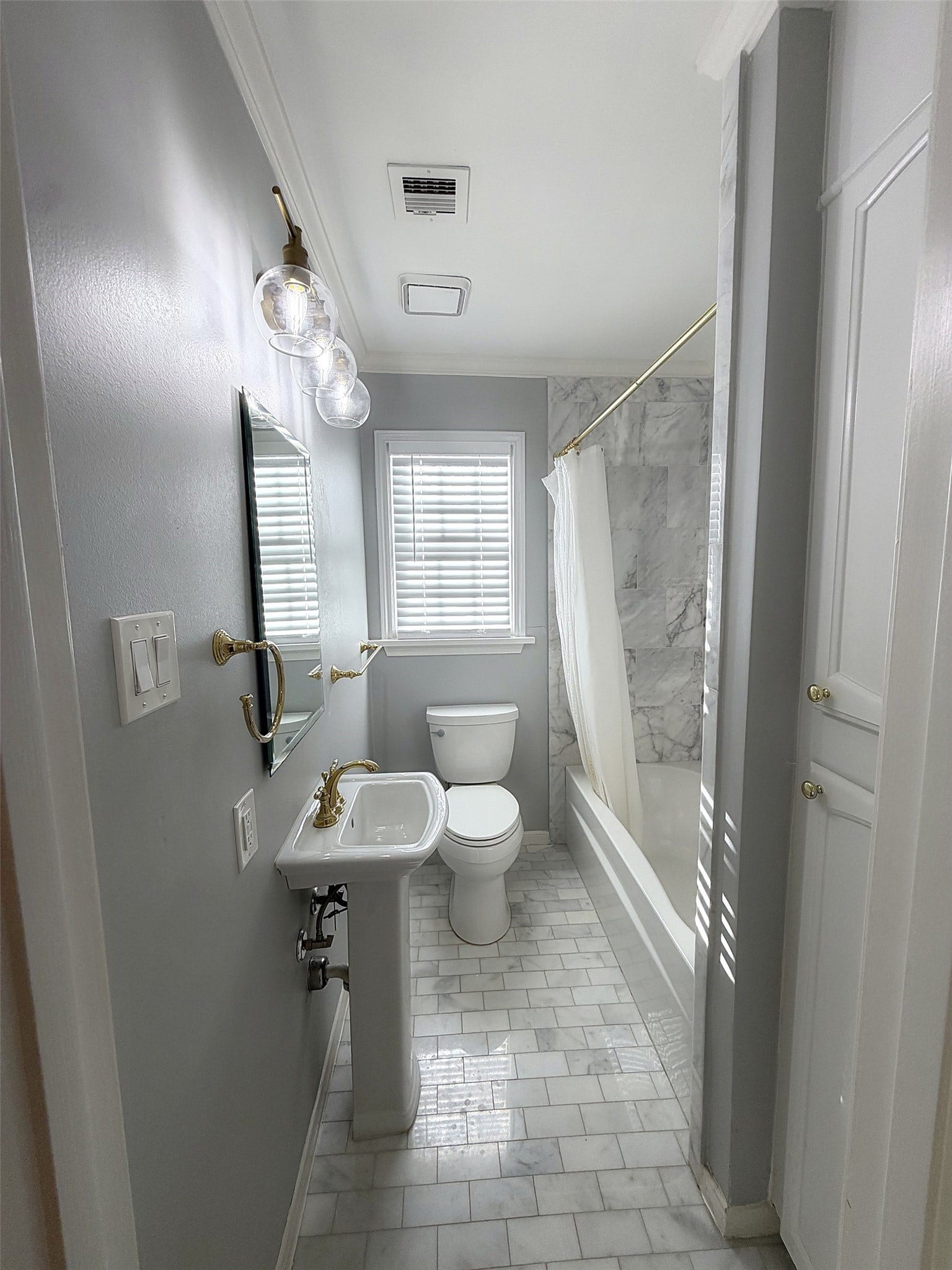 Guest Bathroom: Updated bathroom with a bathtub/shower combination, marble accents, and modern lighting.