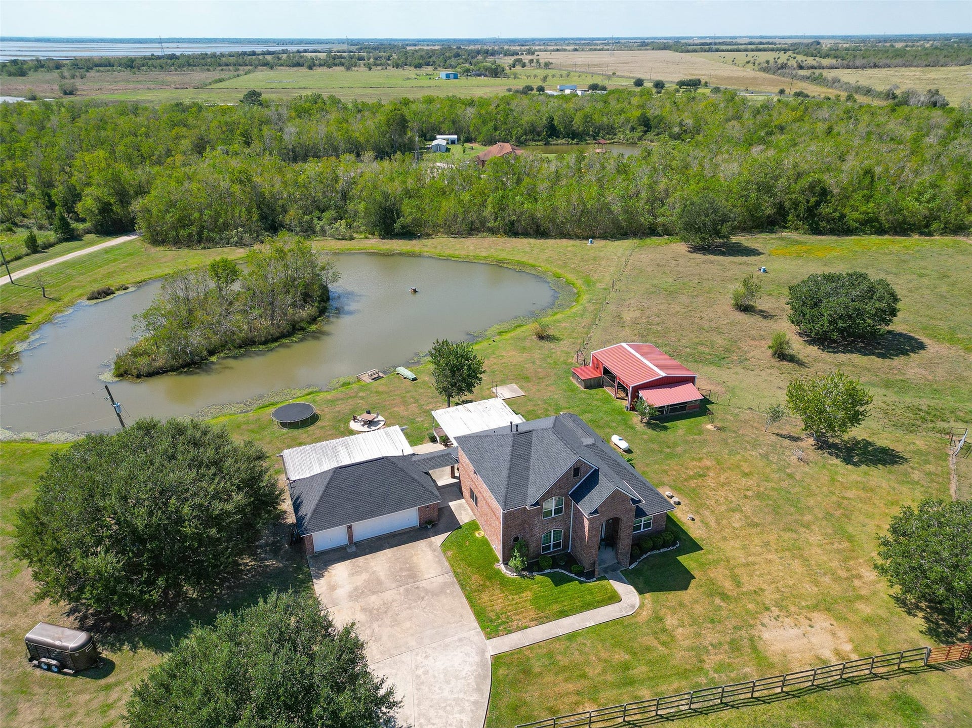 Aerial view of the property showcasing the home, pond, garage and barn