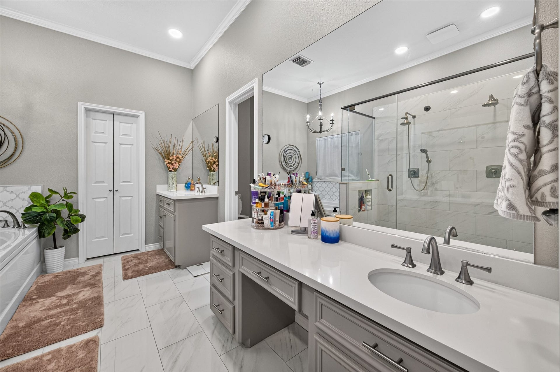 Primary bathroom has an oversize, custom vanity with sitting area