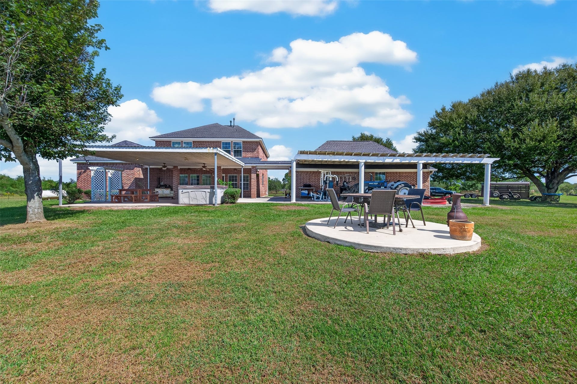 View from the pond looking at the back of the home. Covered pergola is attached to the back of the garage and is where the tractor is stored