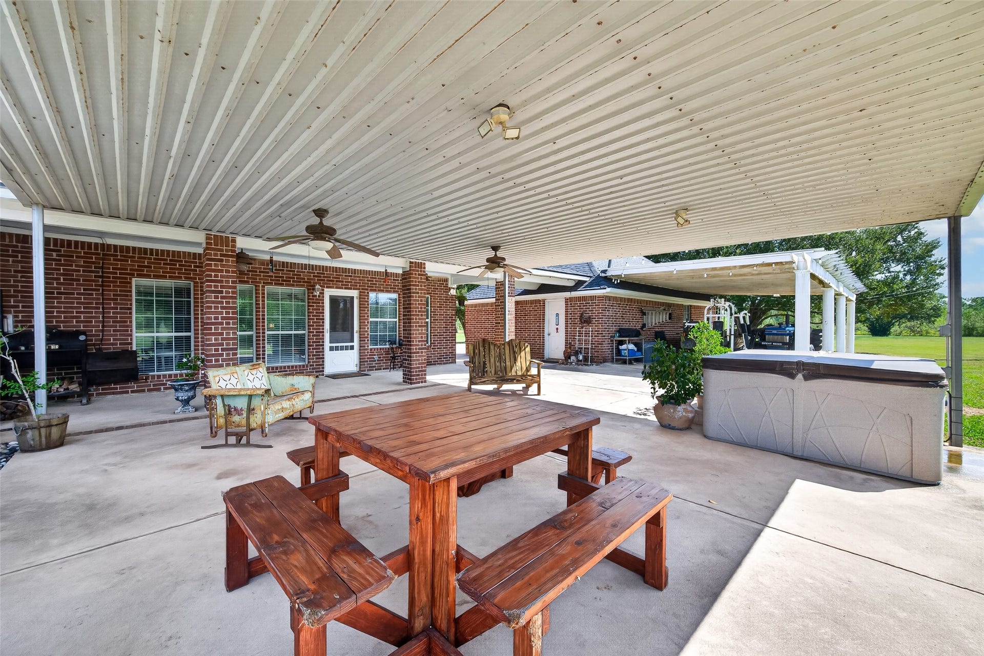 Expansive covered patio with ceiling fans, outdoor dining, and multiple seating areas for entertaining