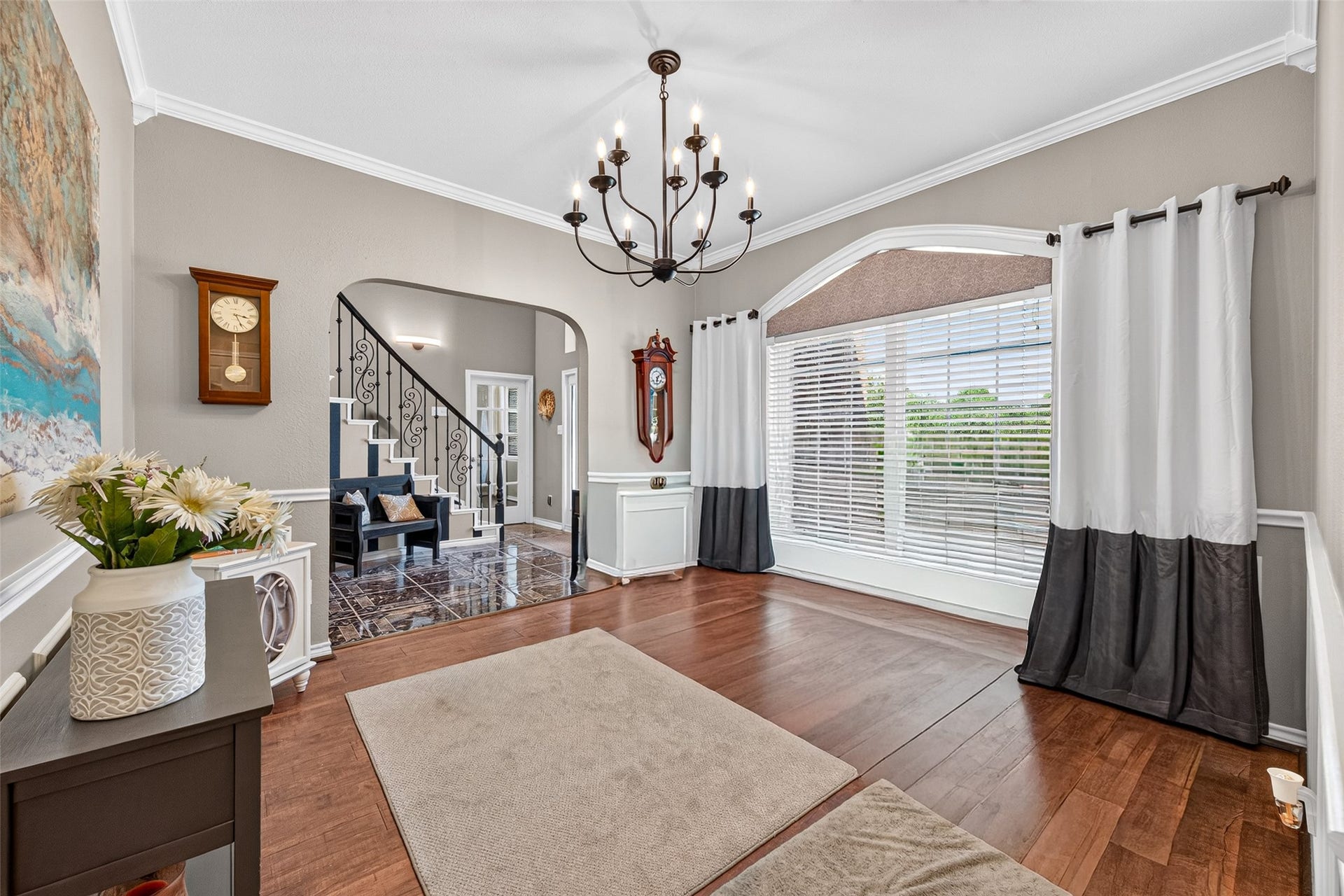 Elegant dining area with statement chandelier and large windows overlooking the front yard