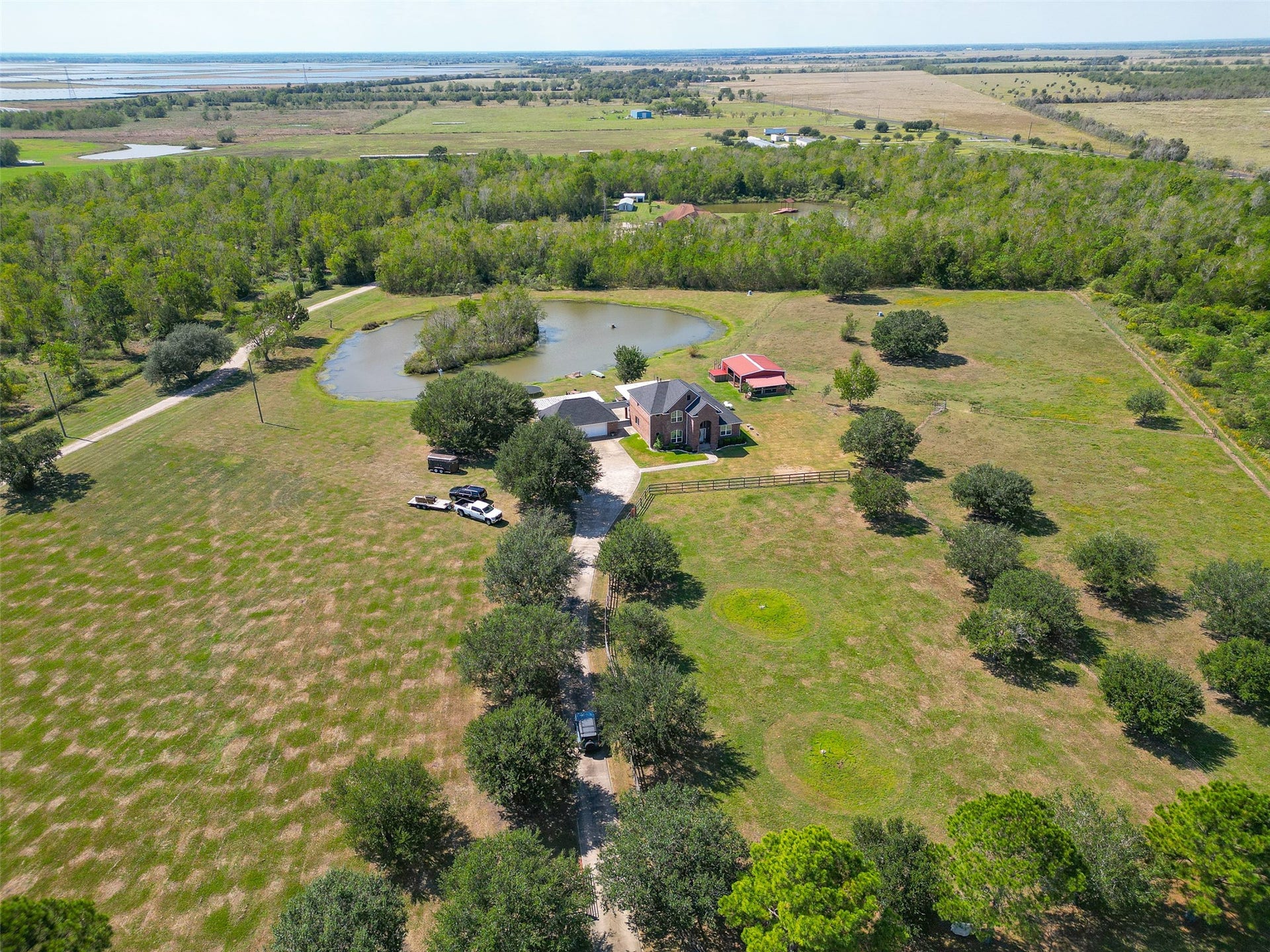 The driveway is surrounded by lush trees. Multiple fruit trees are on the property as well