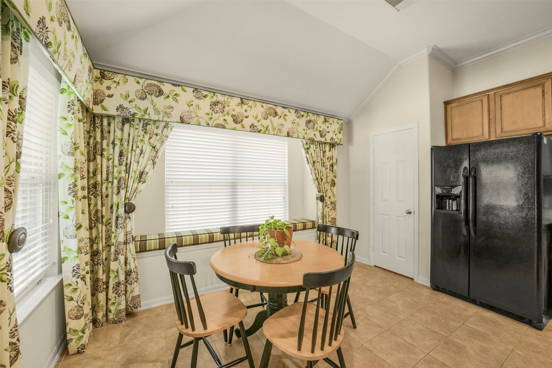 Bright breakfast nook with floral curtains and a cozy window seat.