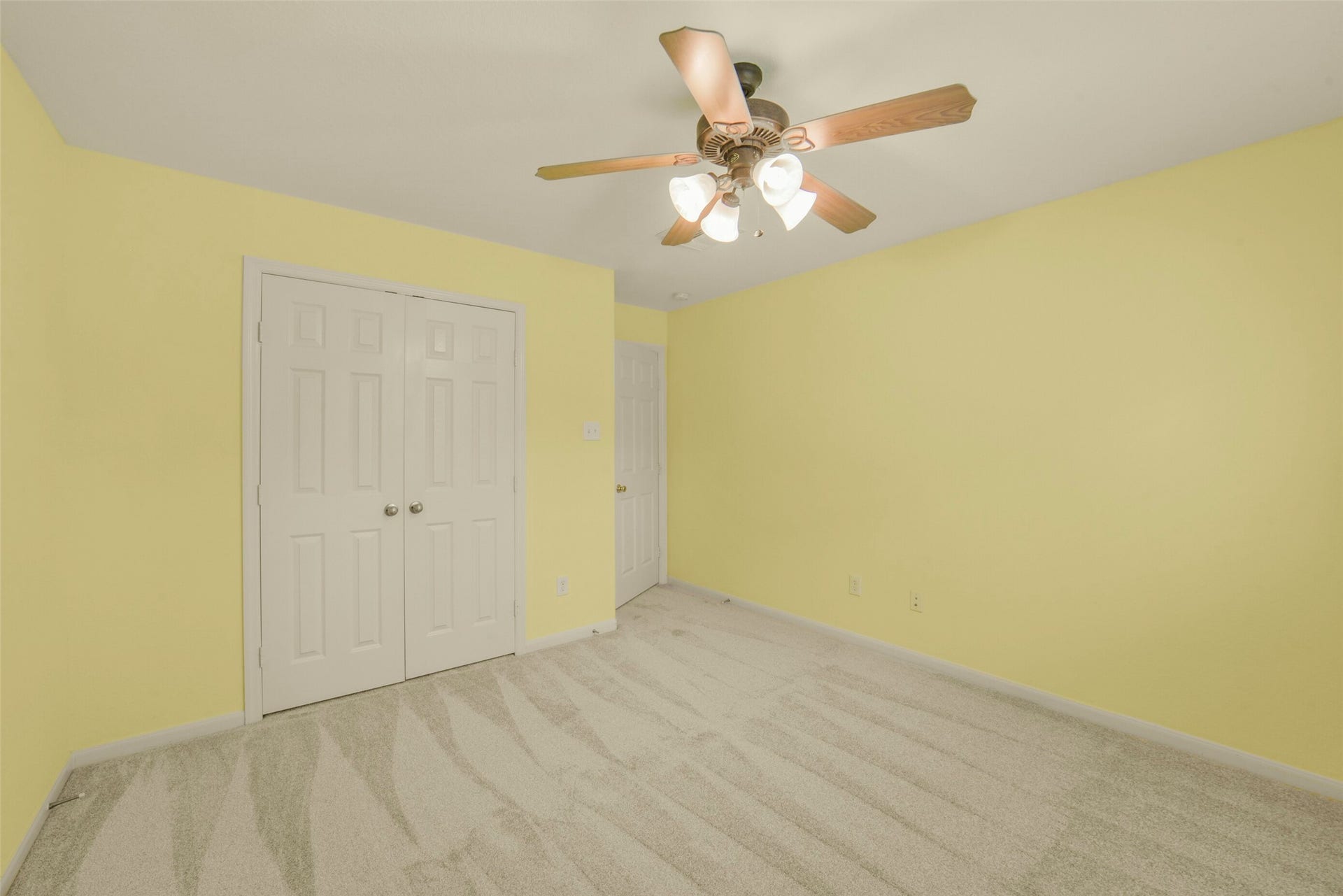 Bright and airy secondary bedroom with plush carpet, and a ceiling fan for comfort.
