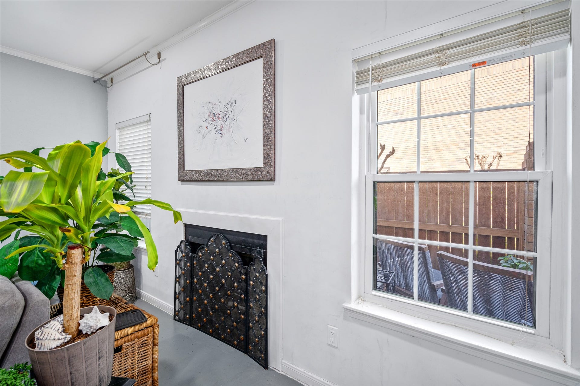 9850 Pagewood Lane, #1302, Houston, TX 77042 This inviting corner of the townhome features a charming fireplace framed by a decorative screen, adding warmth and character to the space. A large window allows for plenty of natural light and offers a view of the private patio, creating a bright and airy atmosphere. The neutral tones and clean design make this the perfect spot to relax and unwind.