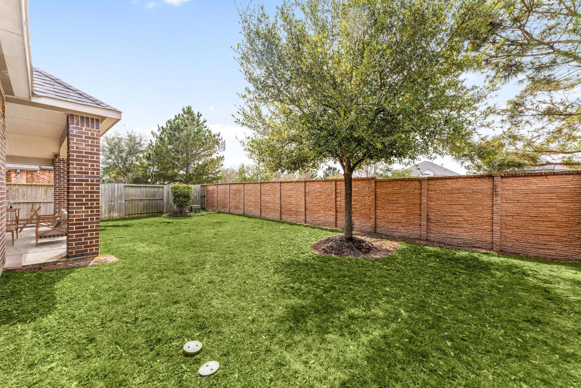 2419 Elmwood Trail, Katy, TX 77493 Spacious backyard with lush green lawn, mature tree, and full privacy brick fence, perfect for relaxing, entertaining, or enjoying outdoor living year-round.