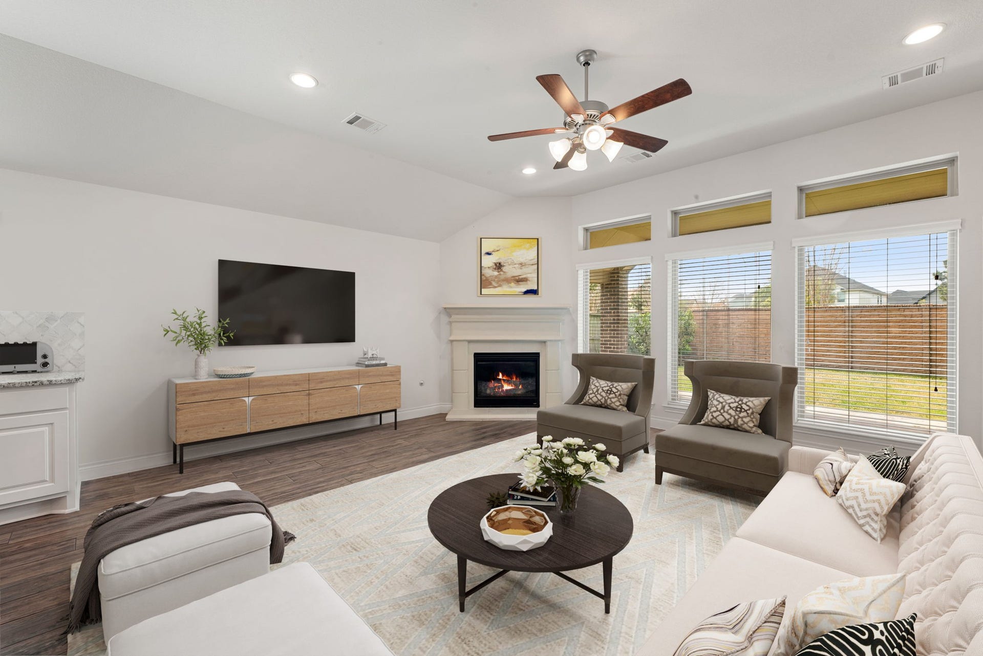 2419 Elmwood Trail, Katy, TX 77493 Spacious living room with high ceilings, abundant natural light, wood-look flooring, cozy fireplace, and large windows overlooking the backyard. Open and inviting layout perfect for relaxing or entertaining.
