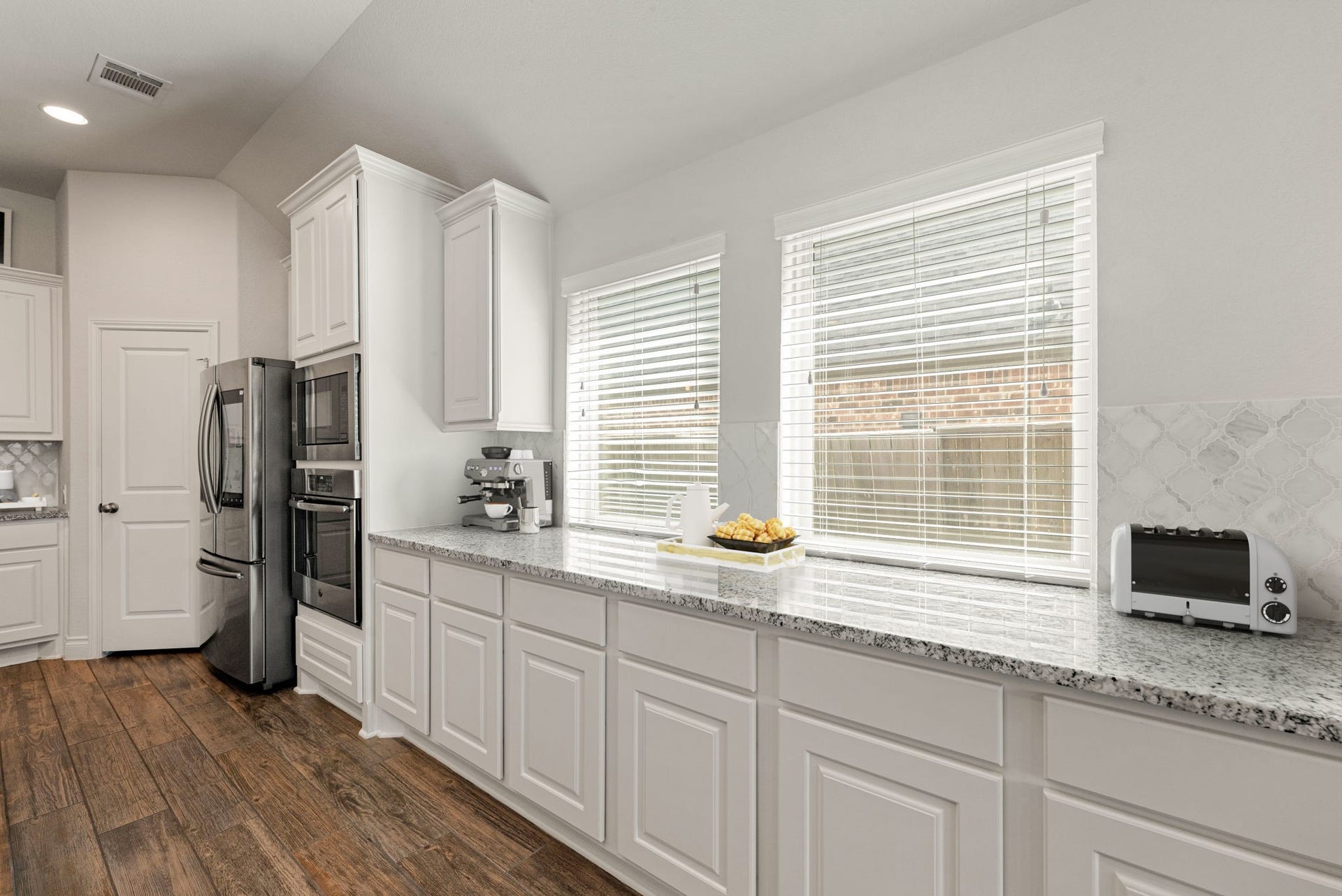 2419 Elmwood Trail, Katy, TX 77493 Kitchen with extended counter space, abundant cabinetry, granite countertops, and large windows providing great natural light. Plenty of storage and prep space, perfect for everyday cooking.