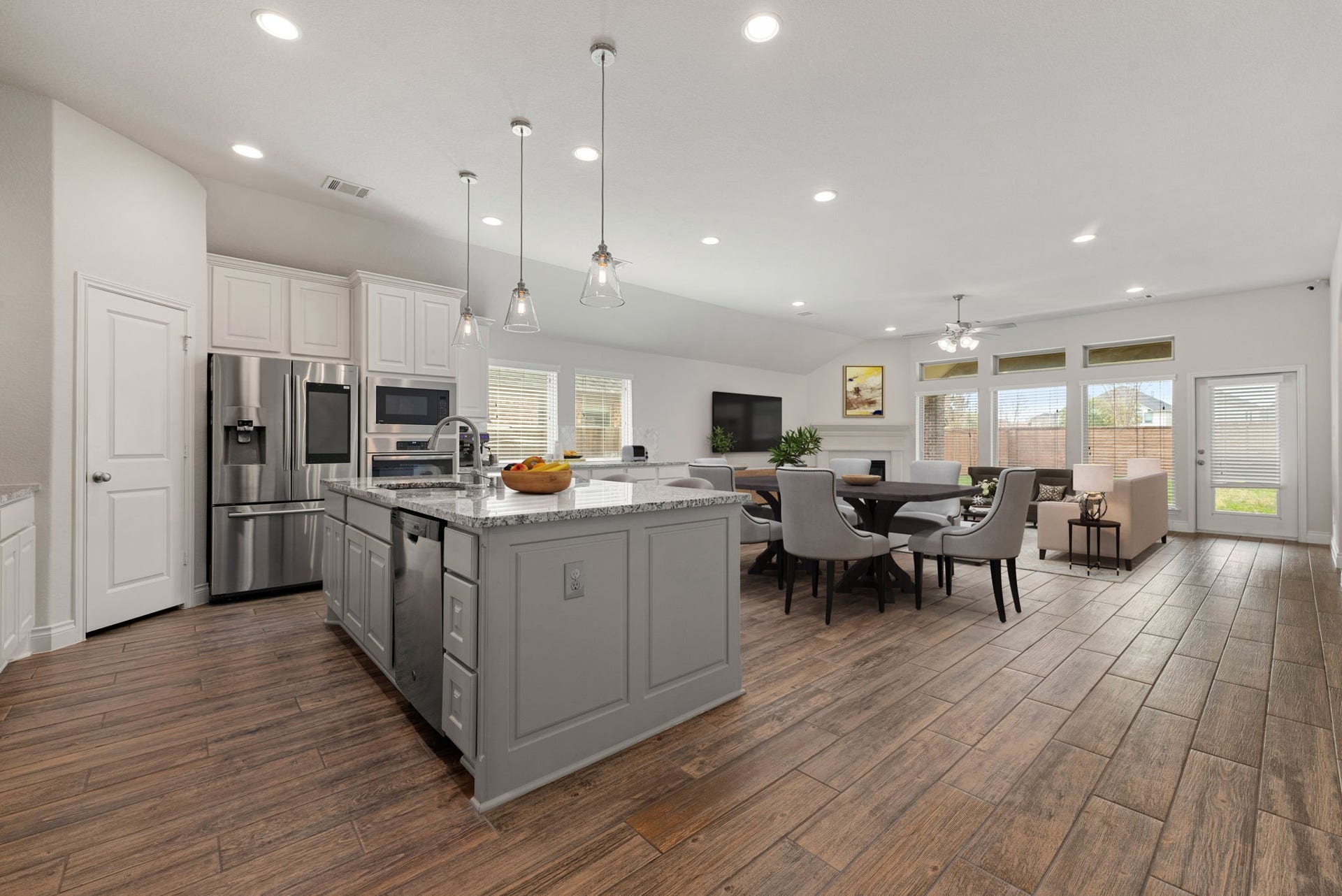 2419 Elmwood Trail, Katy, TX 77493 Open-concept kitchen, dining, and living area featuring a large island with granite countertops, stainless steel appliances, recessed lighting, and wood-look flooring. Spacious layout ideal for entertaining and everyday living.