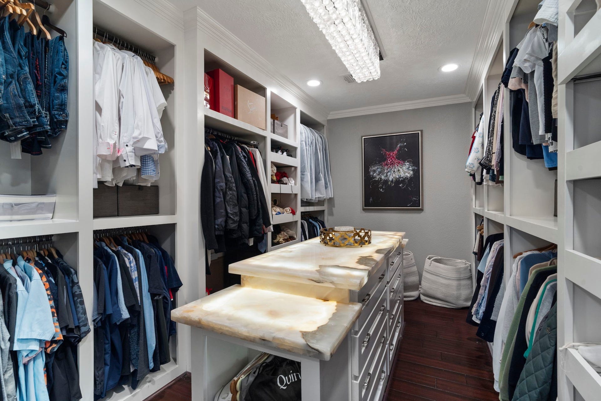 9 Charleston Street S, Sugar Land, TX 77478 An expansive walk-in closet featuring an illuminated honey onyx island and custom built-ins.