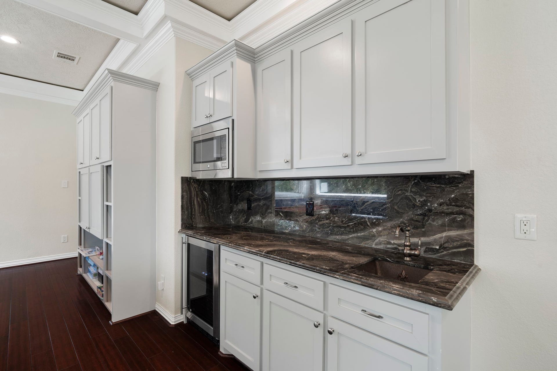 9 Charleston Street S, Sugar Land, TX 77478 The kitchenette features a beverage refrigerator, built-in microwave, sink, ample storage cabinetry, and a gorgeous Italian black lava marble countertop and backsplash.