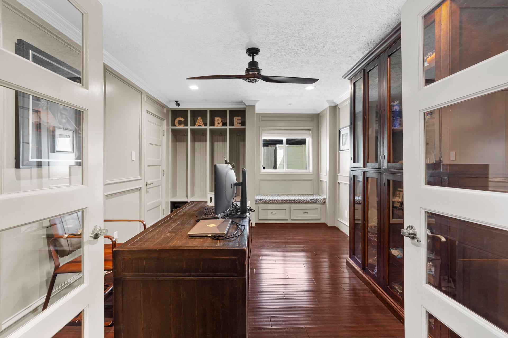 9 Charleston Street S, Sugar Land, TX 77478 Modern glass French doors open to a stylish home office featuring custom built-ins and a charming window seat, creating a bright and inviting space for work, reading, or quiet moments.