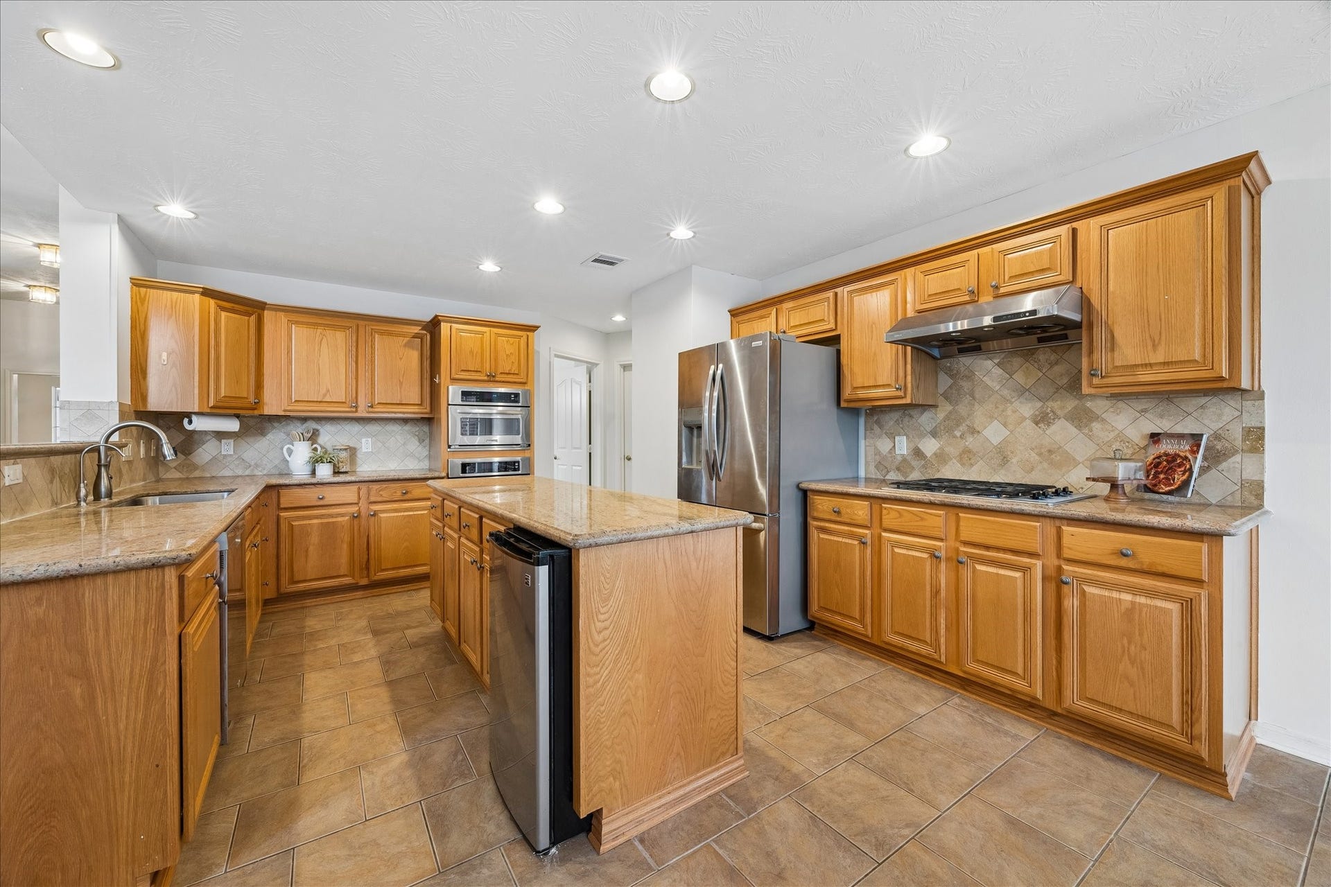 3316 Windfern, Pearland, TX 77581 The kitchen boats granite counters, an island, gas cook top, and built in oven