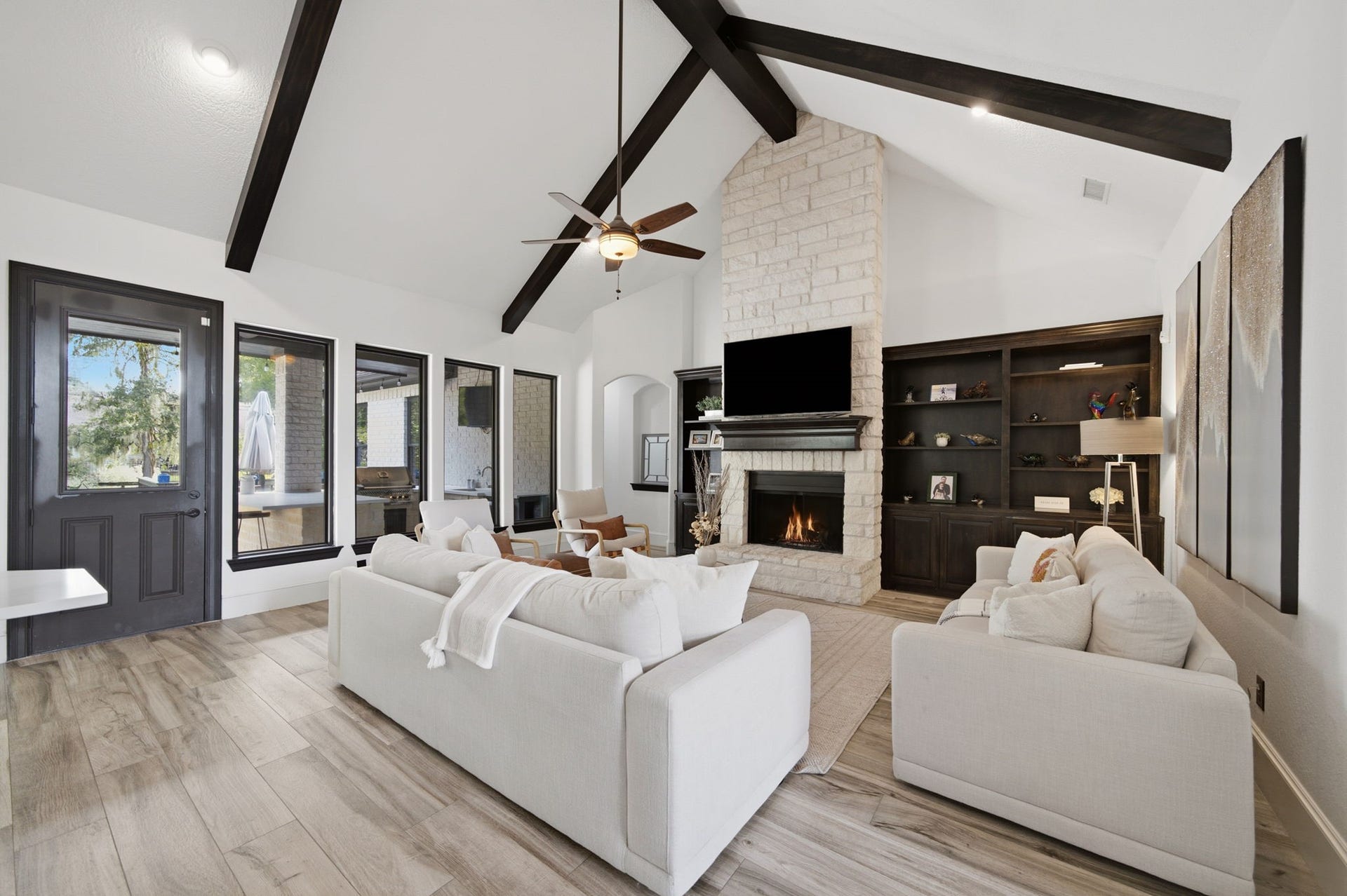 32703 Wales Circle, Fulshear, TX 77441 A soaring beamed cathedral ceiling and floor-to-ceiling stone fireplace create a striking focal point in the family room, while custom built-ins and expansive backyard views add warmth and character.