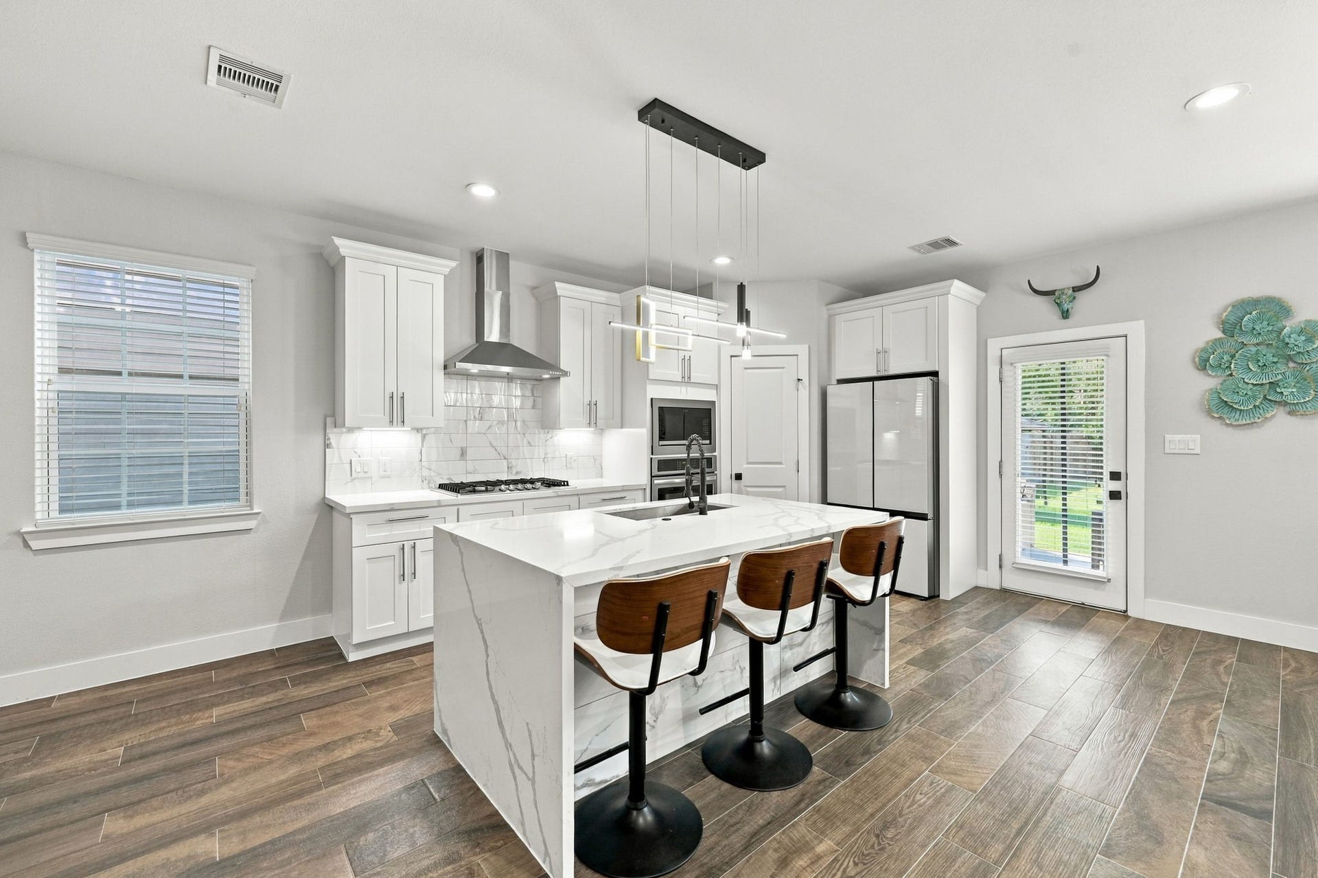 1116 Bennington Street, Houston, TX 77022 Modern kitchen featuring soft-close cabinetry and drawers, white countertops with gray veining and a waterfall-edge island.
