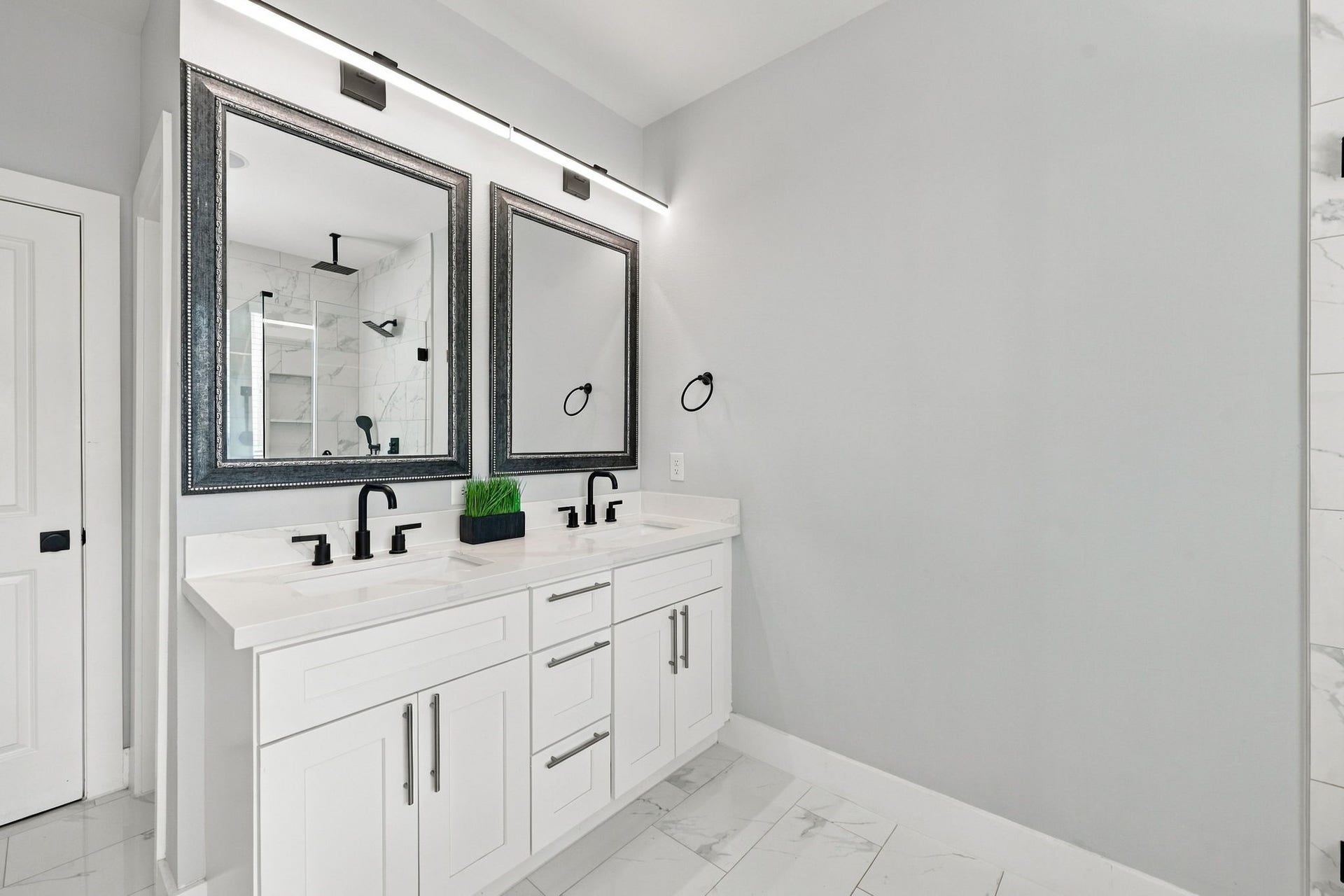 1116 Bennington Street, Houston, TX 77022 Primary bathroom featuring a double vanity with black fixtures, framed mirrors and modern lighting, complemented by a spacious shower and separate soaking tub.