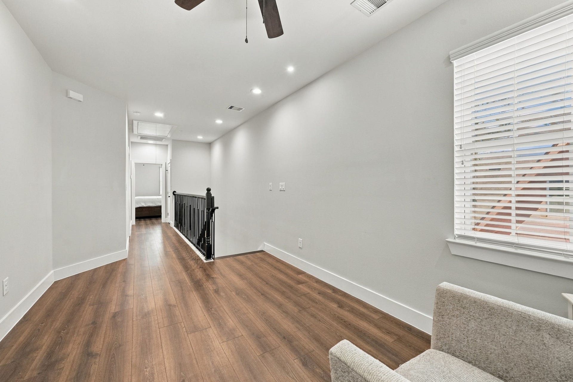 1116 Bennington Street, Houston, TX 77022 Bright 2nd floor hallway featuring sleek floors (NO CARPET!), recessed lighting, and a modern black railing leading to the primary bedroom, with ample natural light.
