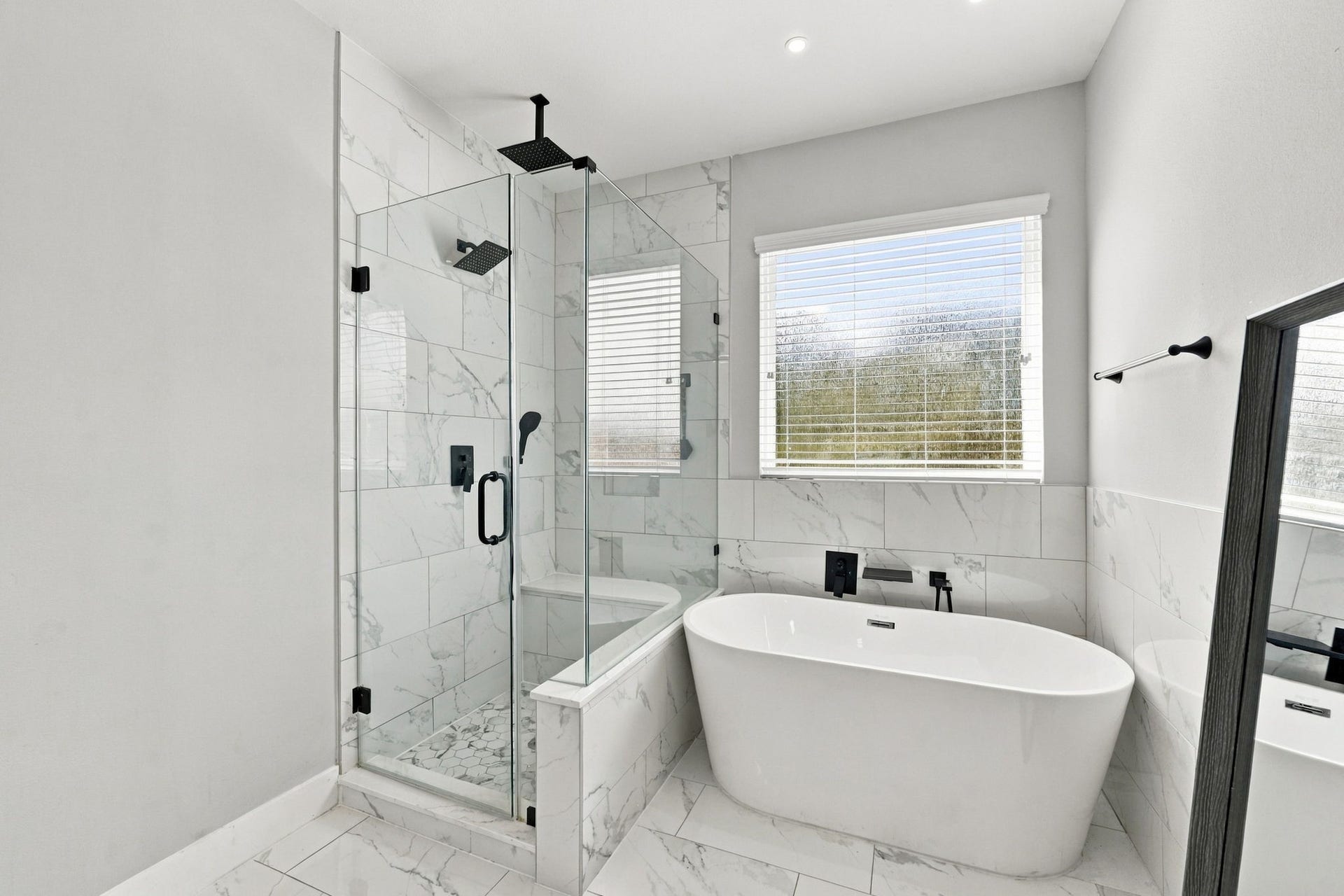 1116 Bennington Street, Houston, TX 77022 Luxurious primary bathroom featuring a glass-enclosed walk-in shower, modern freestanding soaking tub and striking black fixtures.
