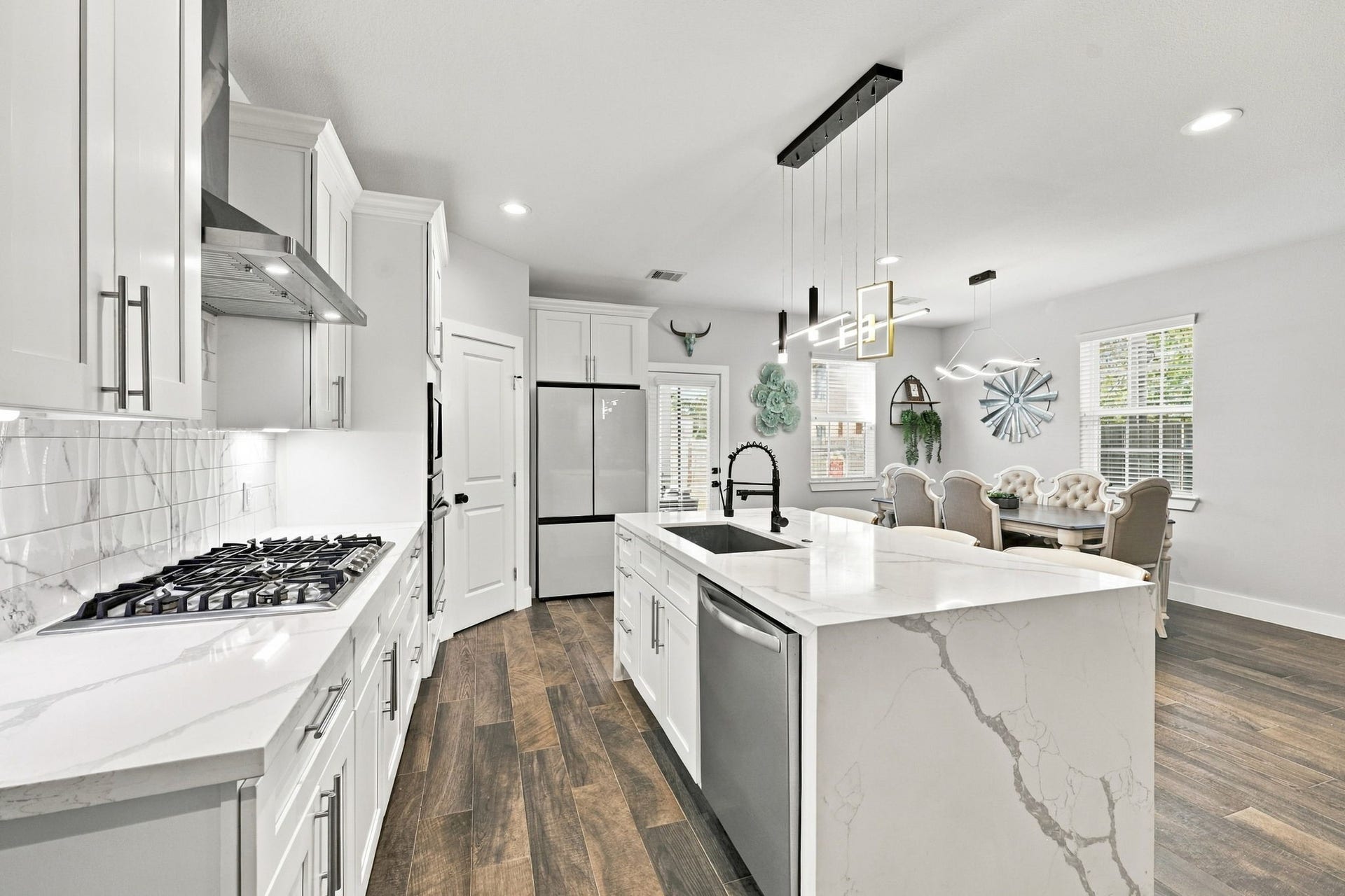 1116 Bennington Street, Houston, TX 77022 Well-appointed kitchen featuring a gas cooktop, stainless steel vent hood, soft-close cabinetry and drawers, and statement pendant lighting.