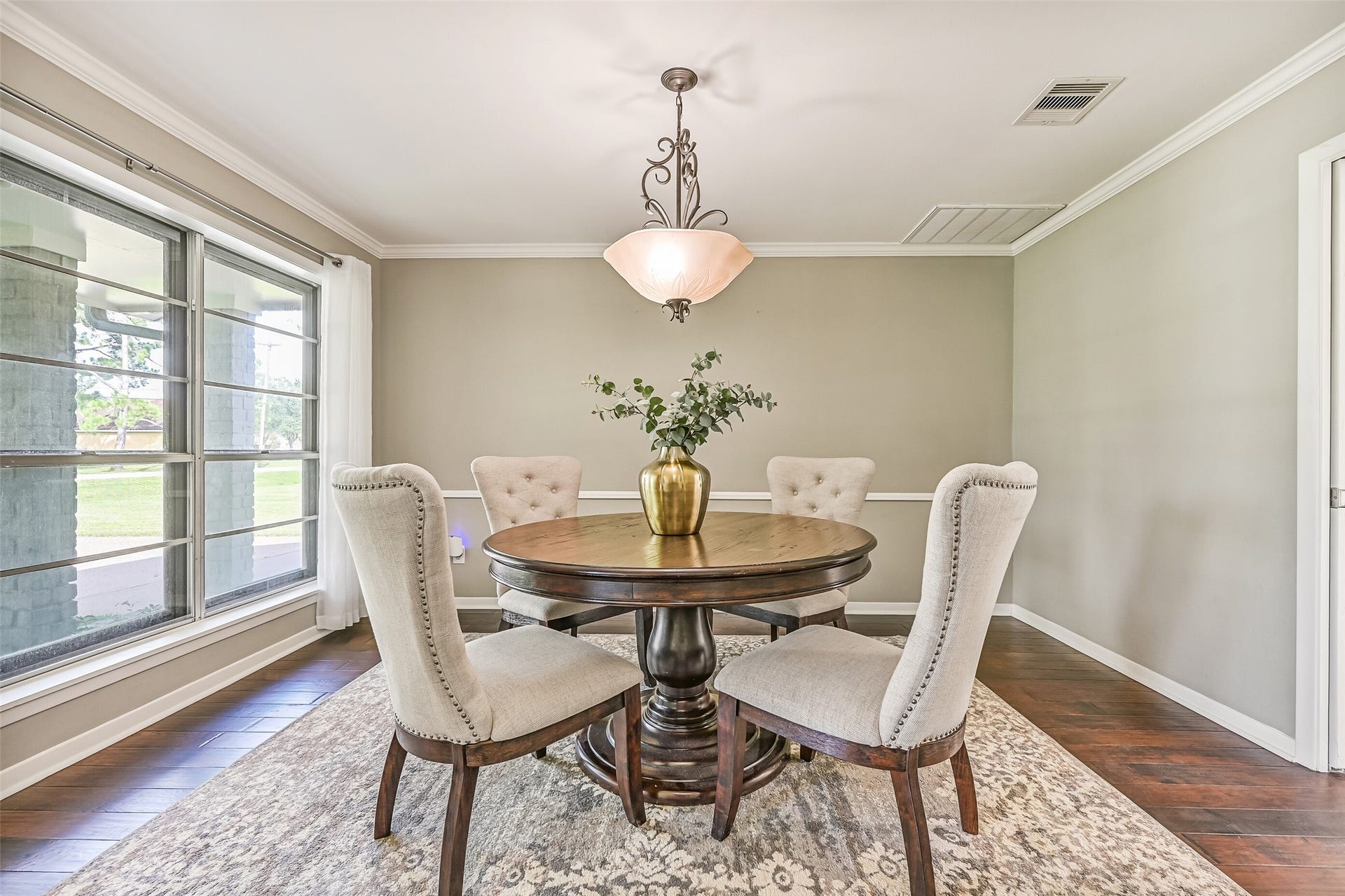 304 Chester Drive, Friendswood, TX 77546 Dining Room First Residence:
Formal dining room featuring wood flooring, crown molding, and a dimmable pendant light fixture, with large windows and breezy draperies showcasing views of the front porch and yard.
