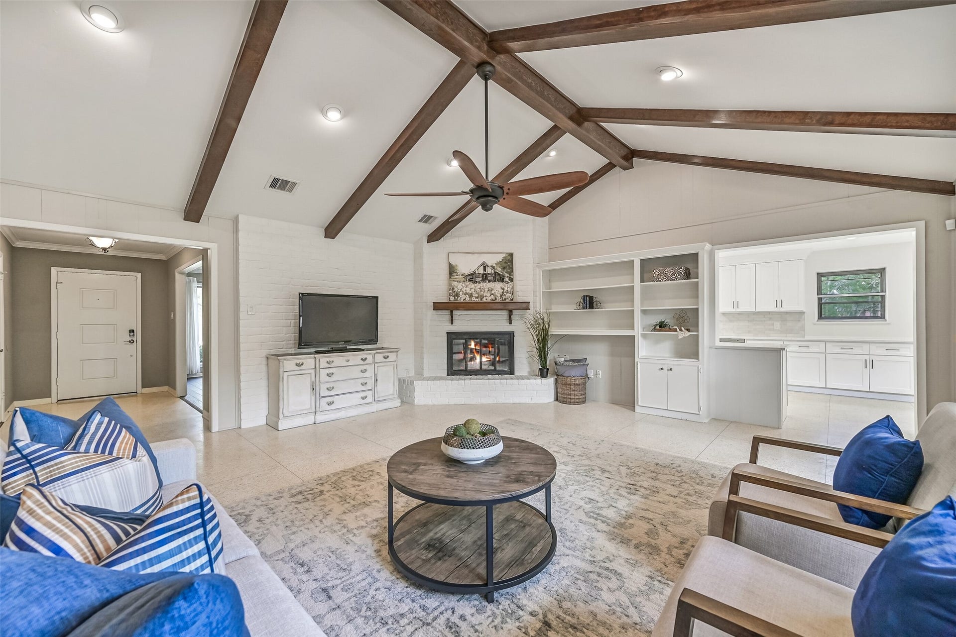 304 Chester Drive, Friendswood, TX 77546 Family Room First Residence:
Step from the foyer into the spacious family room highlighted by a vaulted ceiling with exposed wood beams, recessed lighting, and a ceiling fan, anchored by a painted brick corner-set gas log fireplace and retro terrazzo tile flooring.
