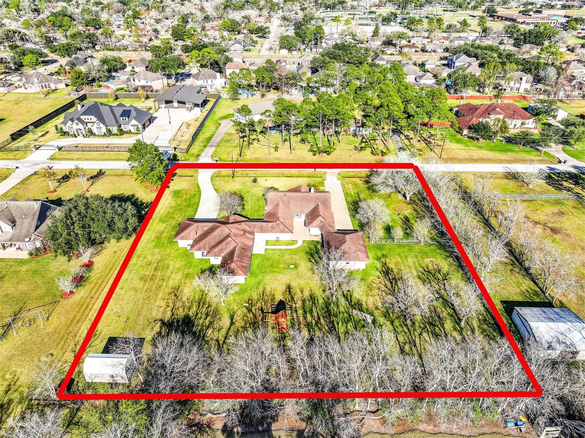 304 Chester Drive, Friendswood, TX 77546 Expansive 1.3-acre Friendswood property boasts a unique dual-residence layout, featuring two complete homes with individual driveways, surrounded by mature trees & wide-open green space. Aerial views showcase the generous lot size with shed, playground, finished garage space, & desirable location on a quiet street with no HOA!