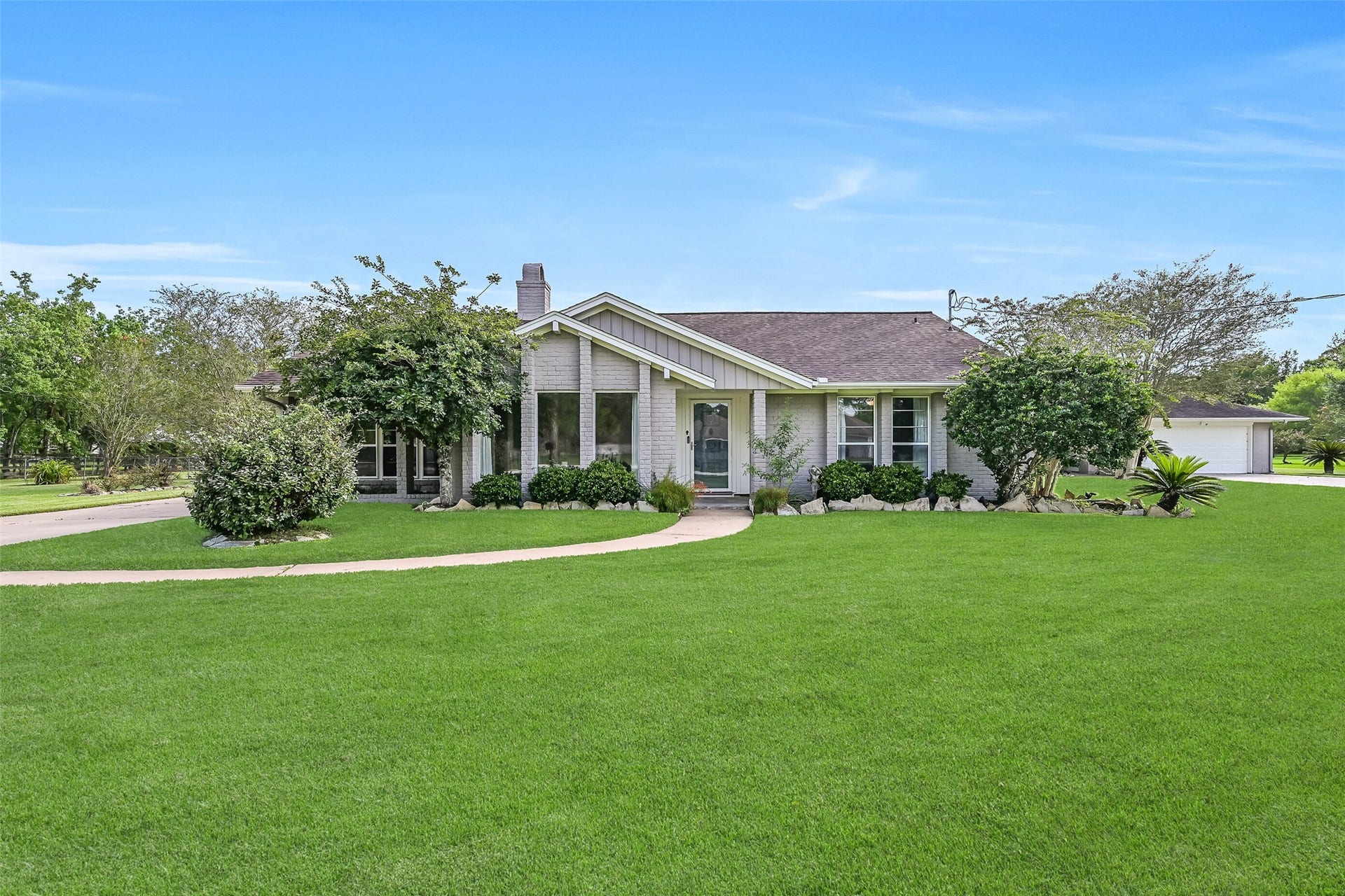 304 Chester Drive, Friendswood, TX 77546 Front Elevation First Residence:
The first residence boasts a classic painted brick exterior with a covered entry, manicured landscaping, and a long private driveway, all positioned on a spacious 1.3-acre lot.