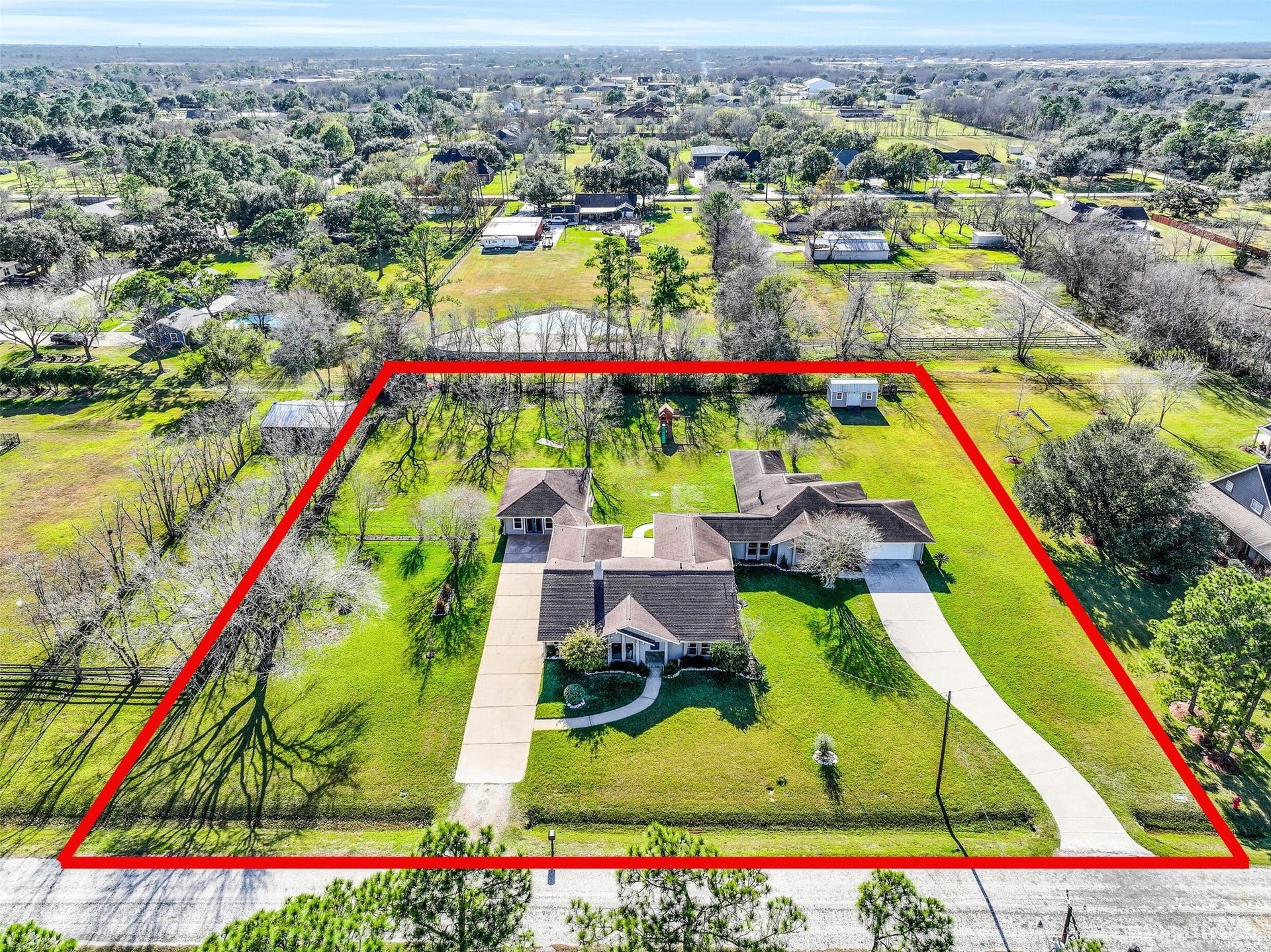 304 Chester Drive, Friendswood, TX 77546 Expansive 1.3-acre Friendswood property boasts a unique dual-residence layout, featuring two complete homes with individual driveways, surrounded by mature trees & wide-open green space. Aerial views showcase the generous lot size with shed, playground, finished garage space, & desirable location on a quiet street with no HOA!