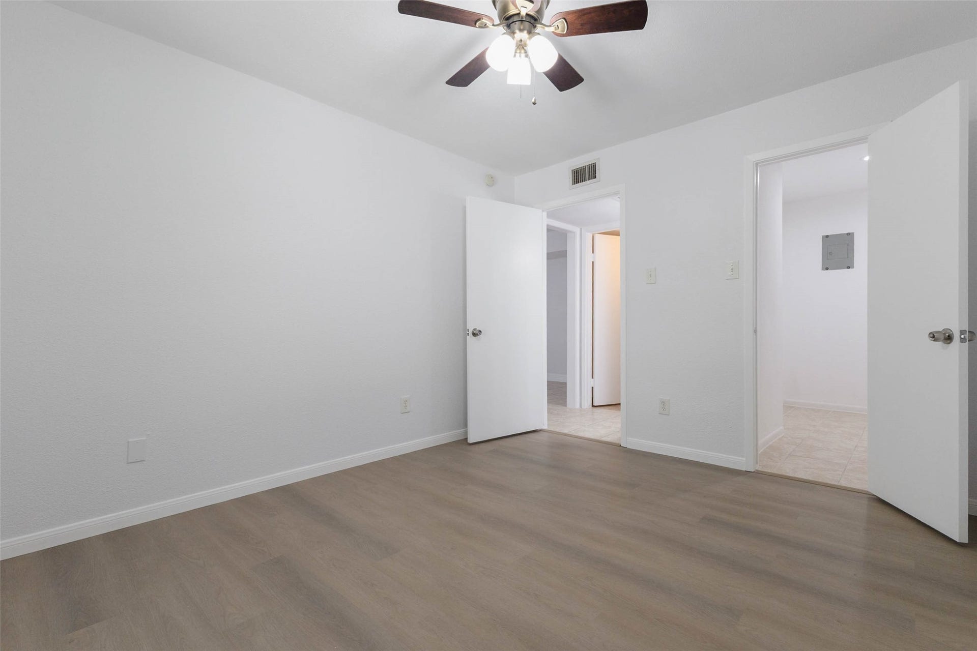 2800 Jeanetta Street, #2207, Houston, TX 77063 Bright and airy room featuring fresh white walls, sleek wood flooring, and a modern ceiling fan, offering a versatile space for your needs.