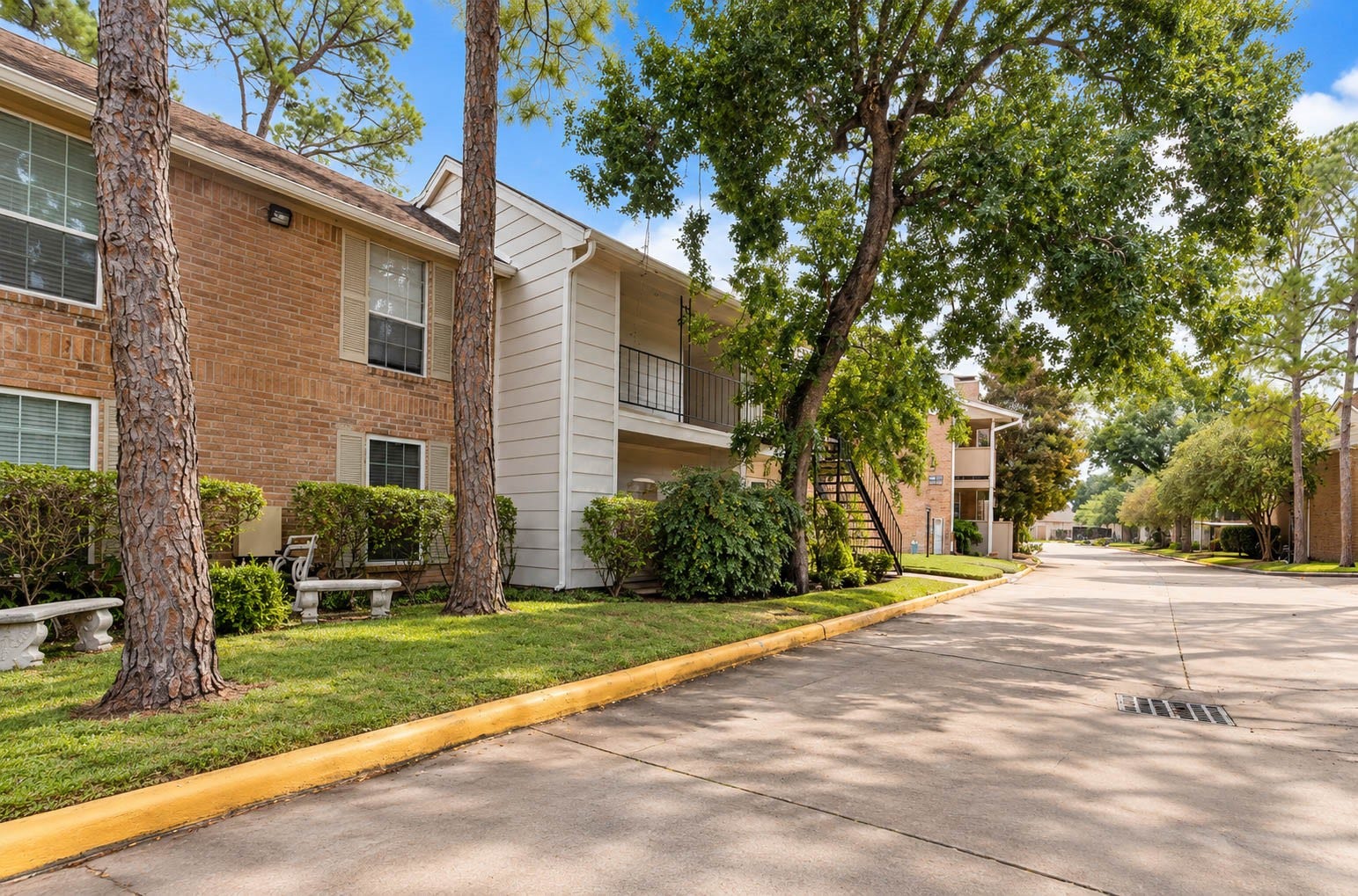 2800 Jeanetta Street, #2207, Houston, TX 77063 Charming brick apartment complex nestled among mature trees, offering a serene environment with well-maintained landscaping and peaceful pathways.