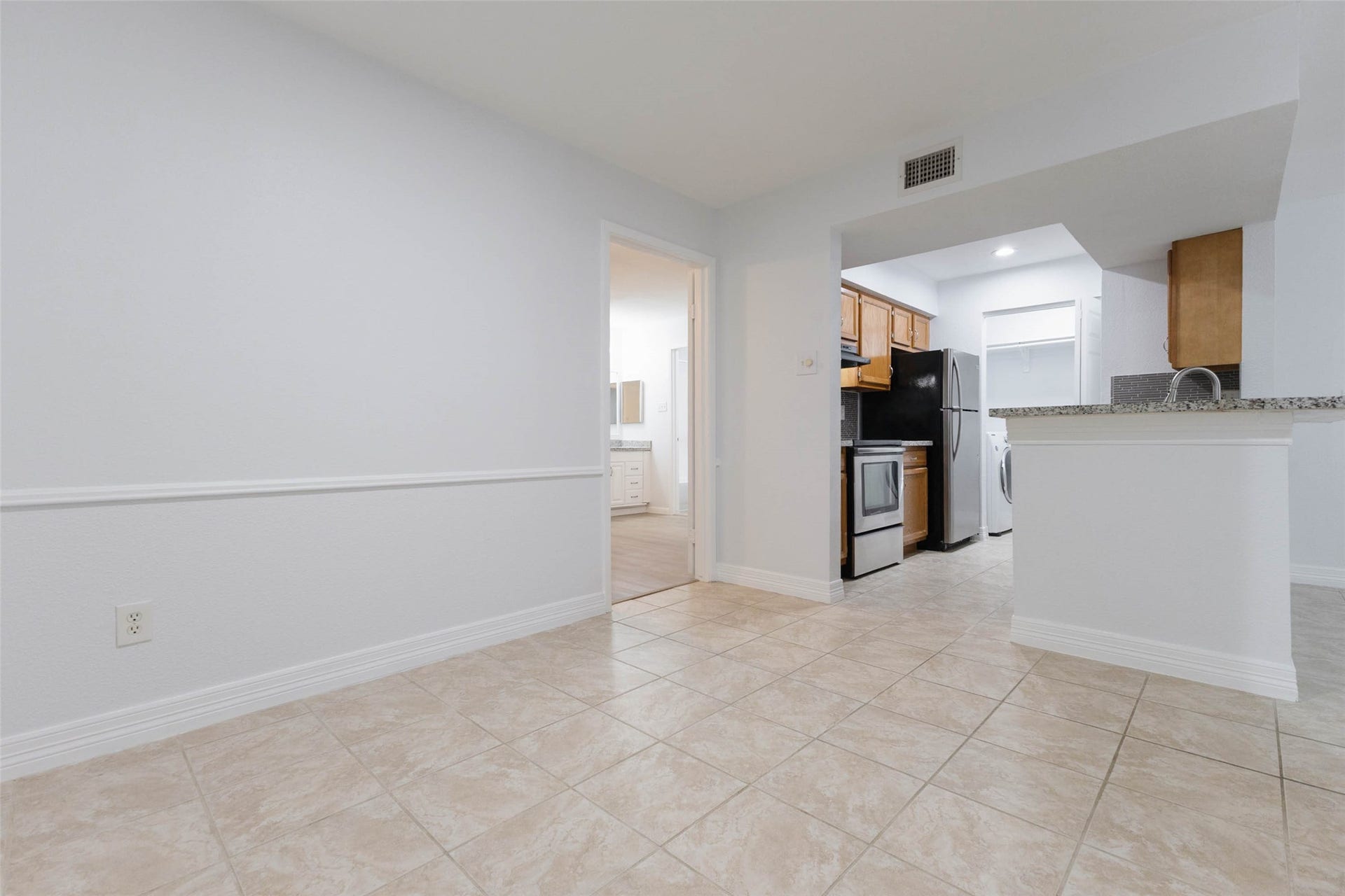 2800 Jeanetta Street, #2207, Houston, TX 77063 Bright, open space with tiled flooring connects to a modern kitchen featuring stainless steel appliances and granite countertops, leading to a cozy dining area.