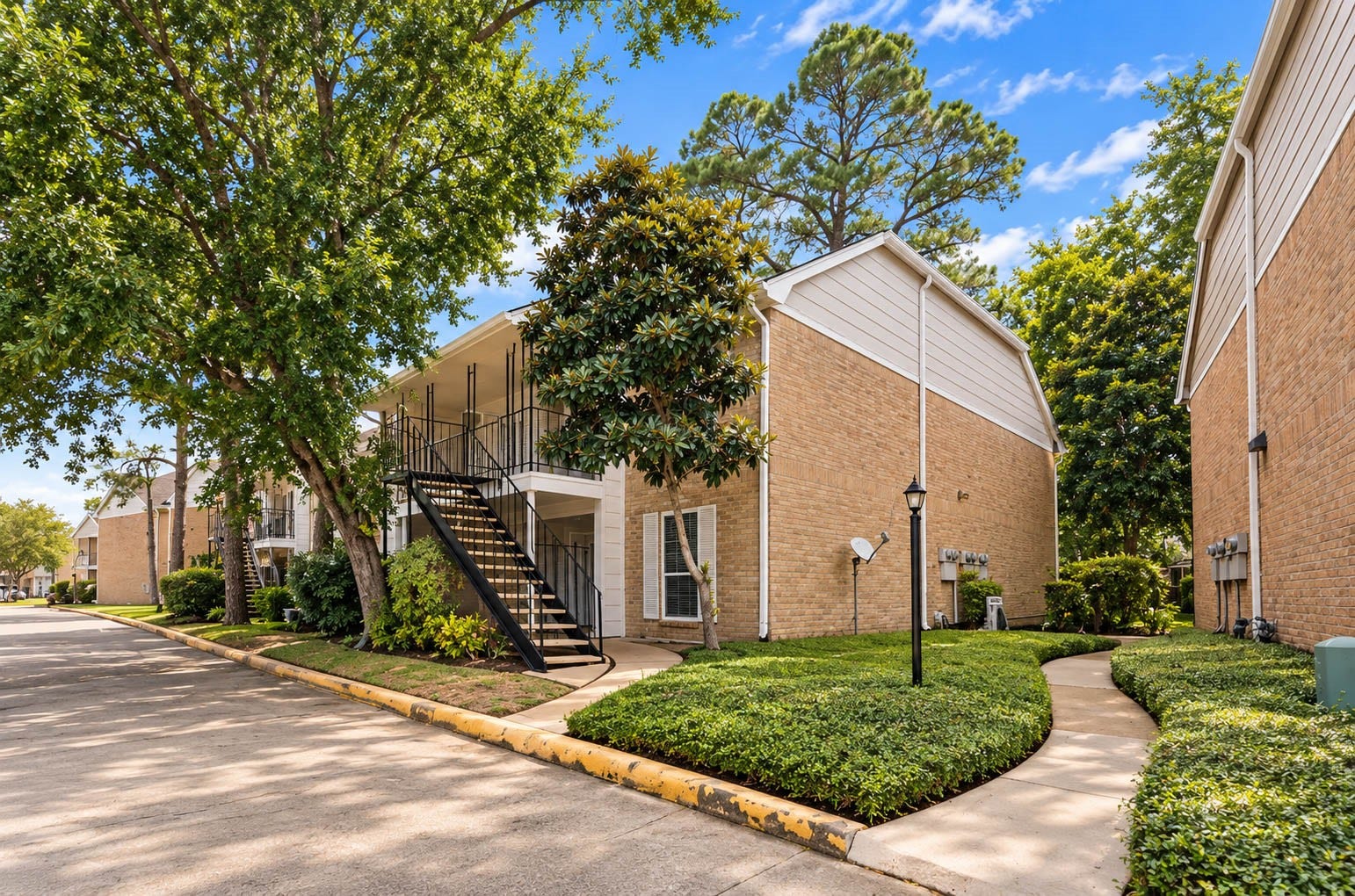 2800 Jeanetta Street, #2207, Houston, TX 77063 Charming brick townhouse with lush landscaping, a private stairway entrance, and a tranquil community setting.