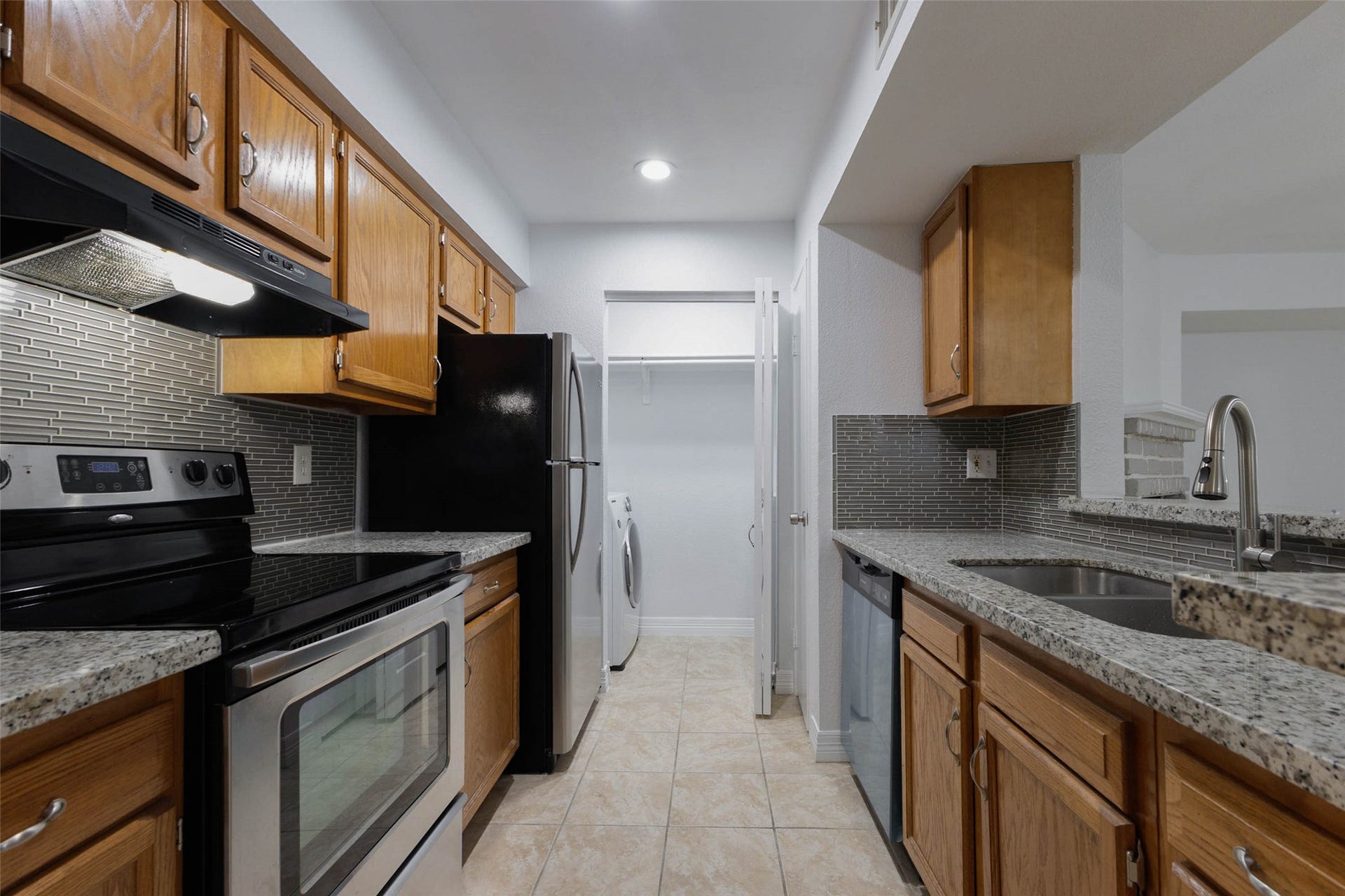 2800 Jeanetta Street, #2207, Houston, TX 77063 Modern kitchen with stainless steel appliances, granite countertops, and warm wooden cabinetry, featuring a stylish tile backsplash and convenient layout.