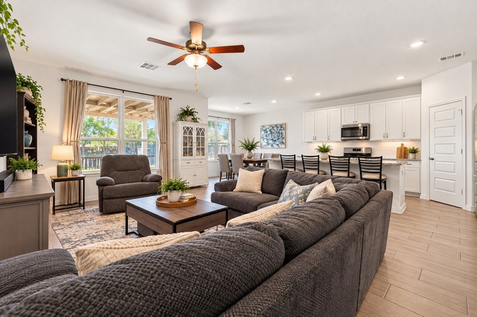 Family room open to kitchen, with ceiling fan and easy to care for wood look tile.
