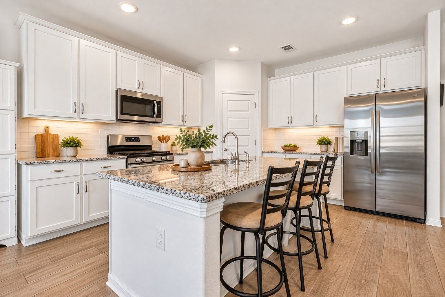 Modern recessed lighting, granite counter tops, huge island with space for eating and entertaining, stainless steel appliances, under cabinet lighting, abundance of cabinets, elegant backsplash, modern five panel interior doors, and wood look tile in all common areas.