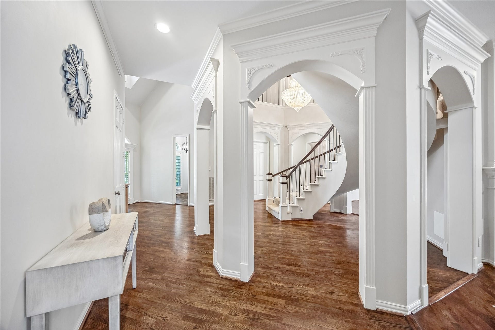 The entry space is bright and inviting, with detailed molding and a chic chandelier adding a touch of luxury.