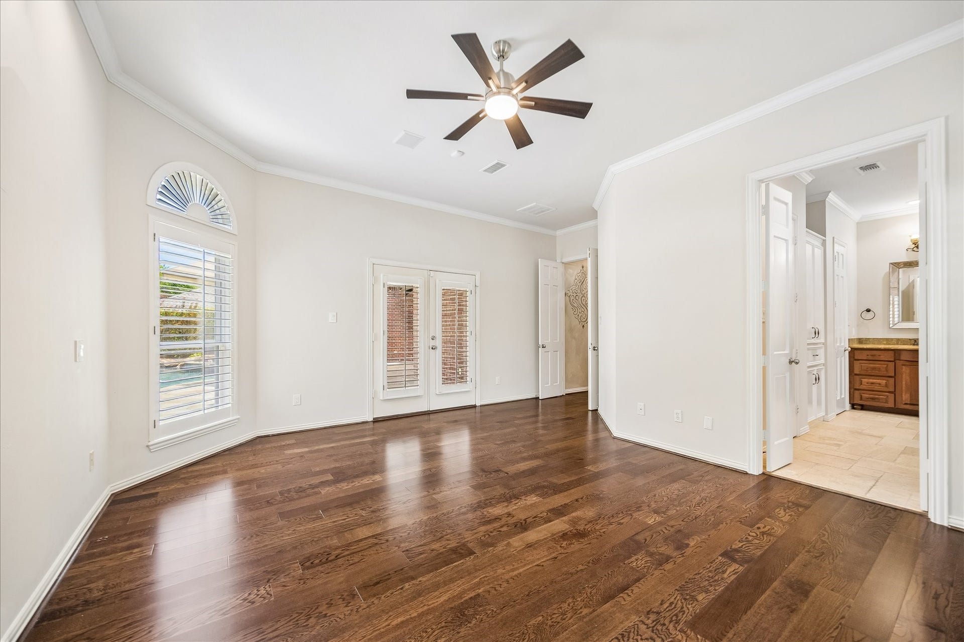 Another view of the primary suite that offers direct access to the private backyard. Also, through elegant French doors, the adjoining spa-inspired bathroom creates a serene, welcoming retreat designed for comfort and relaxation.