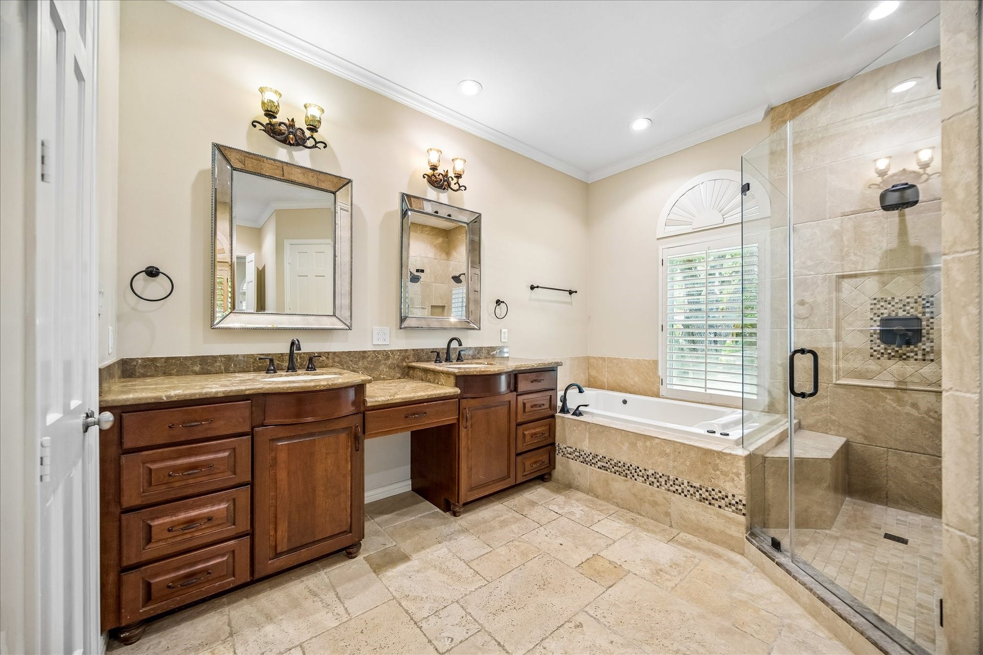A spacious soaking tub with decorative tile accents serves as the focal point, while warm overhead lighting enhances the room's inviting and relaxing ambiance.